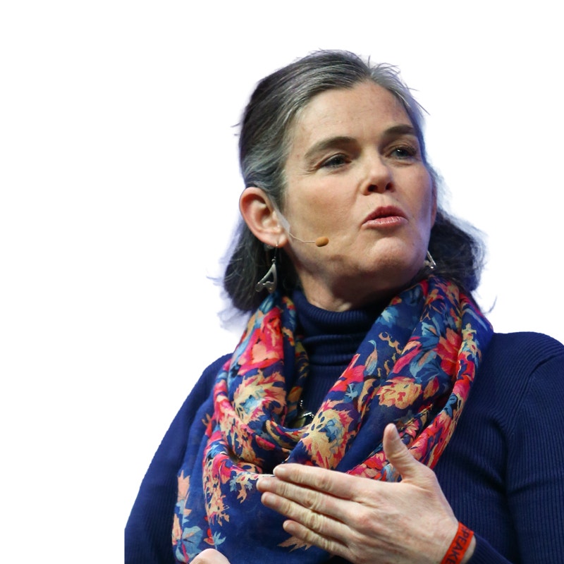 Porträttfoto av en kvinna med mörkt hår som bär en marinblå tröja och ett färgglatt mönstrat scarf.