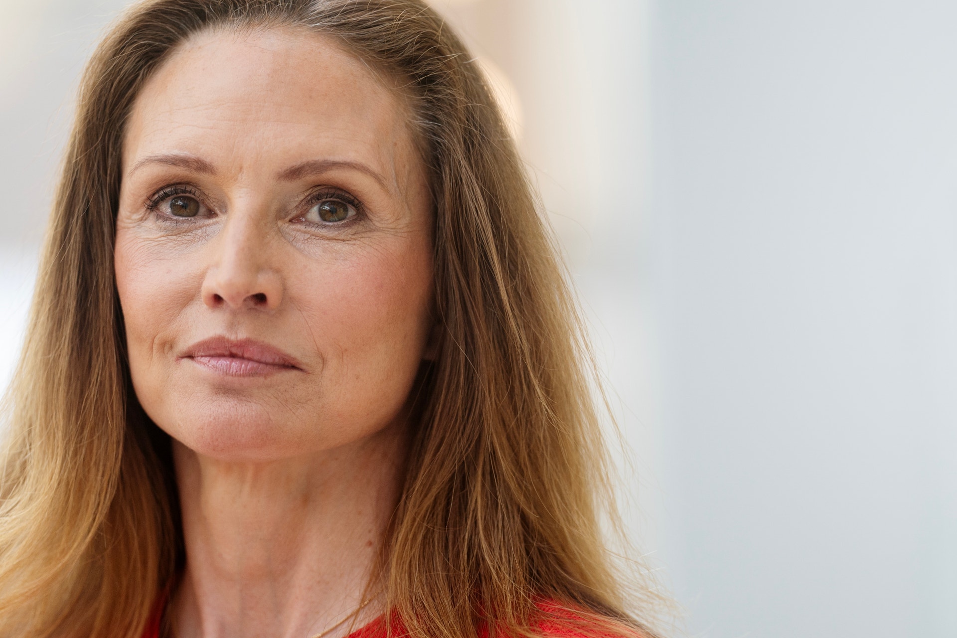 Porträtt av Patricia Hedelius, kvinna med långt rödbrunt hår, iklädd röd tröja.