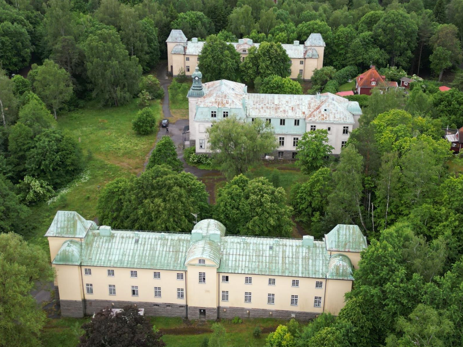 Bilden visar slottsliknande byggnader som är till salu i Motala. Byggnaderna är vita med grått/grönt tak. 