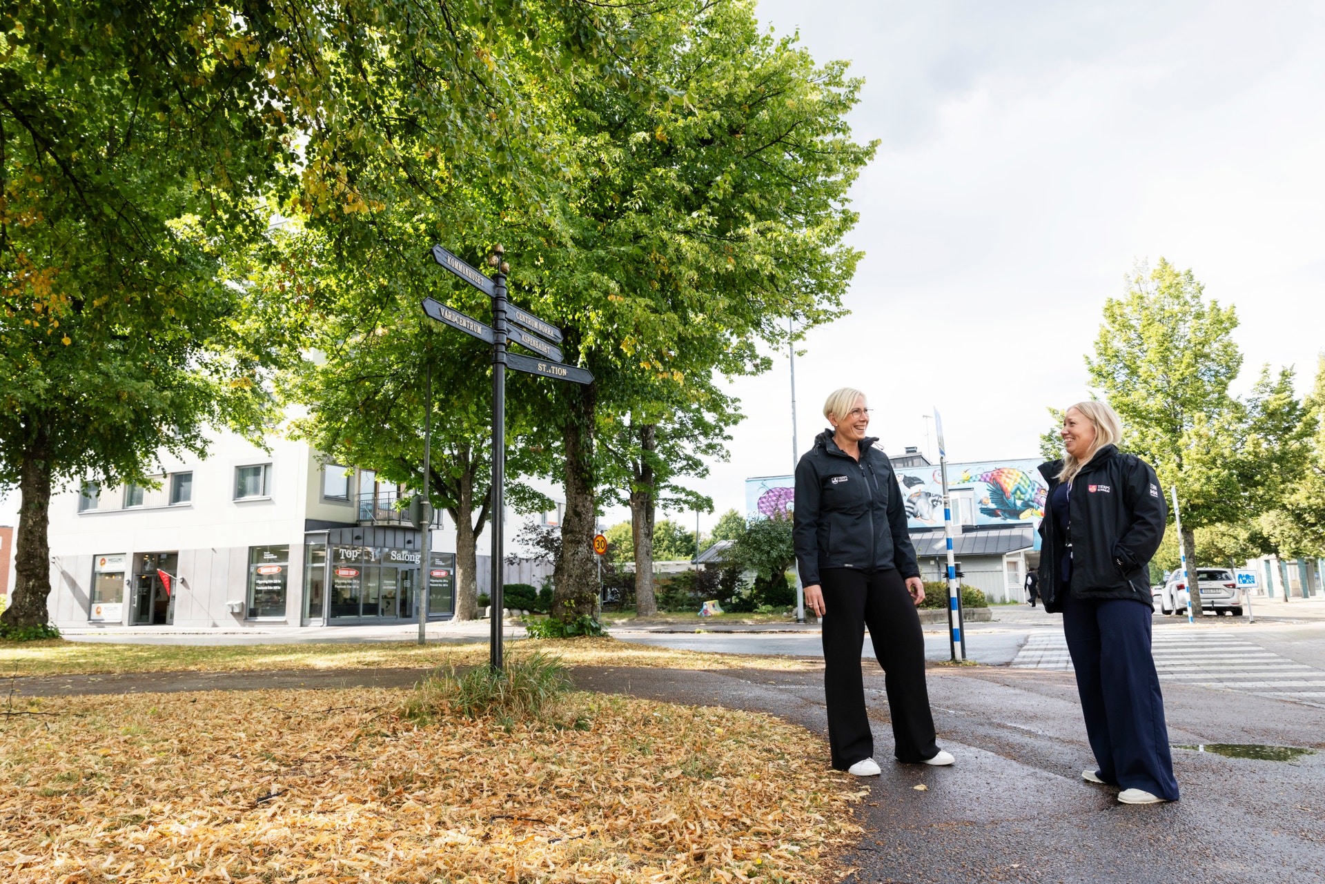 En kvinna med långt blont hår sitter inomhus och tittar åt sidan.