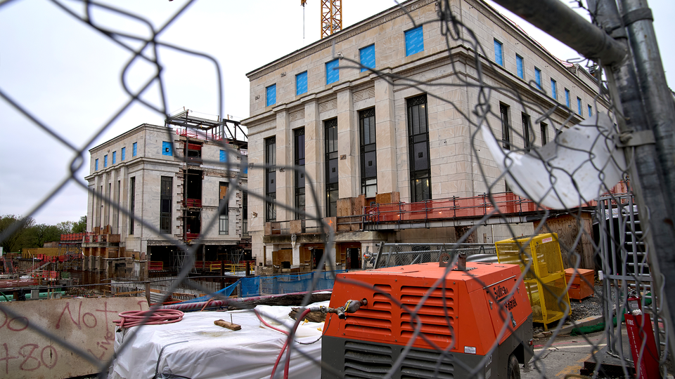 Centralbanken utför omfattande renovering. Framför byggnaden står byggstaket, flera lyftkranar och containrar.