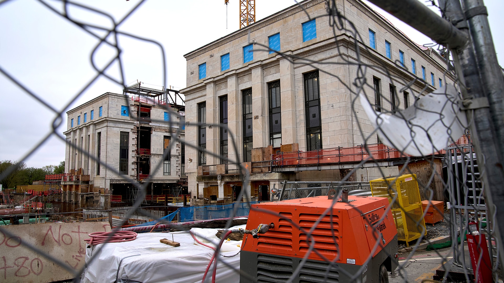 Centralbanken utför omfattande renovering. Framför byggnaden står byggstaket, flera lyftkranar och containrar.