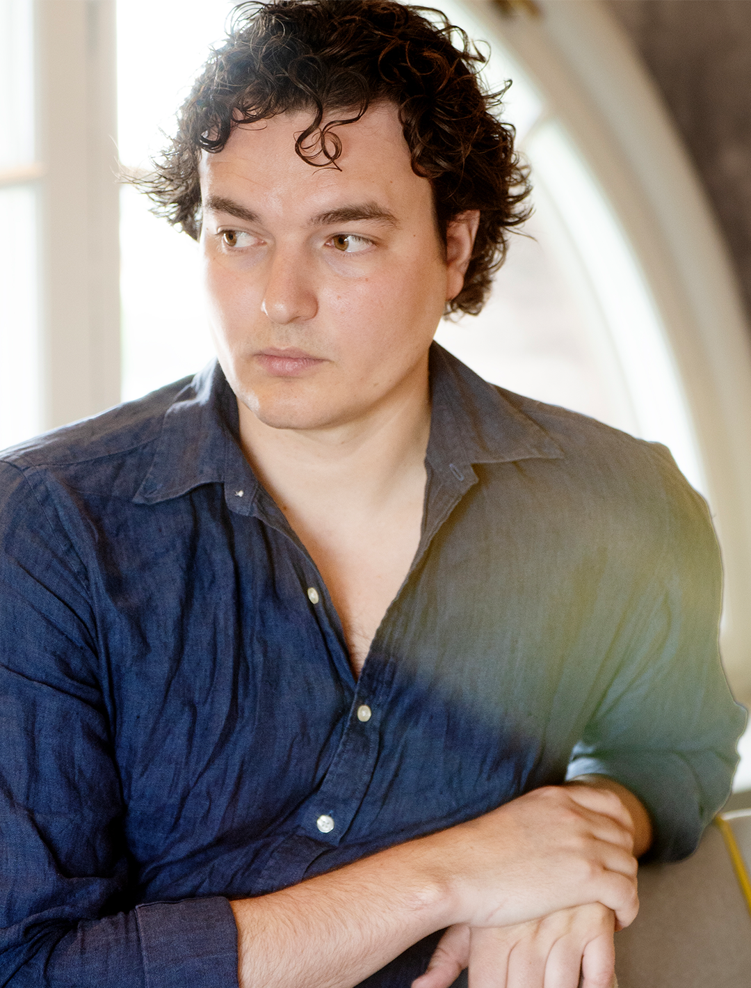 Antonio Melani står och lutar sig skrivbordet. Han har en blå linneskjorta på sig.