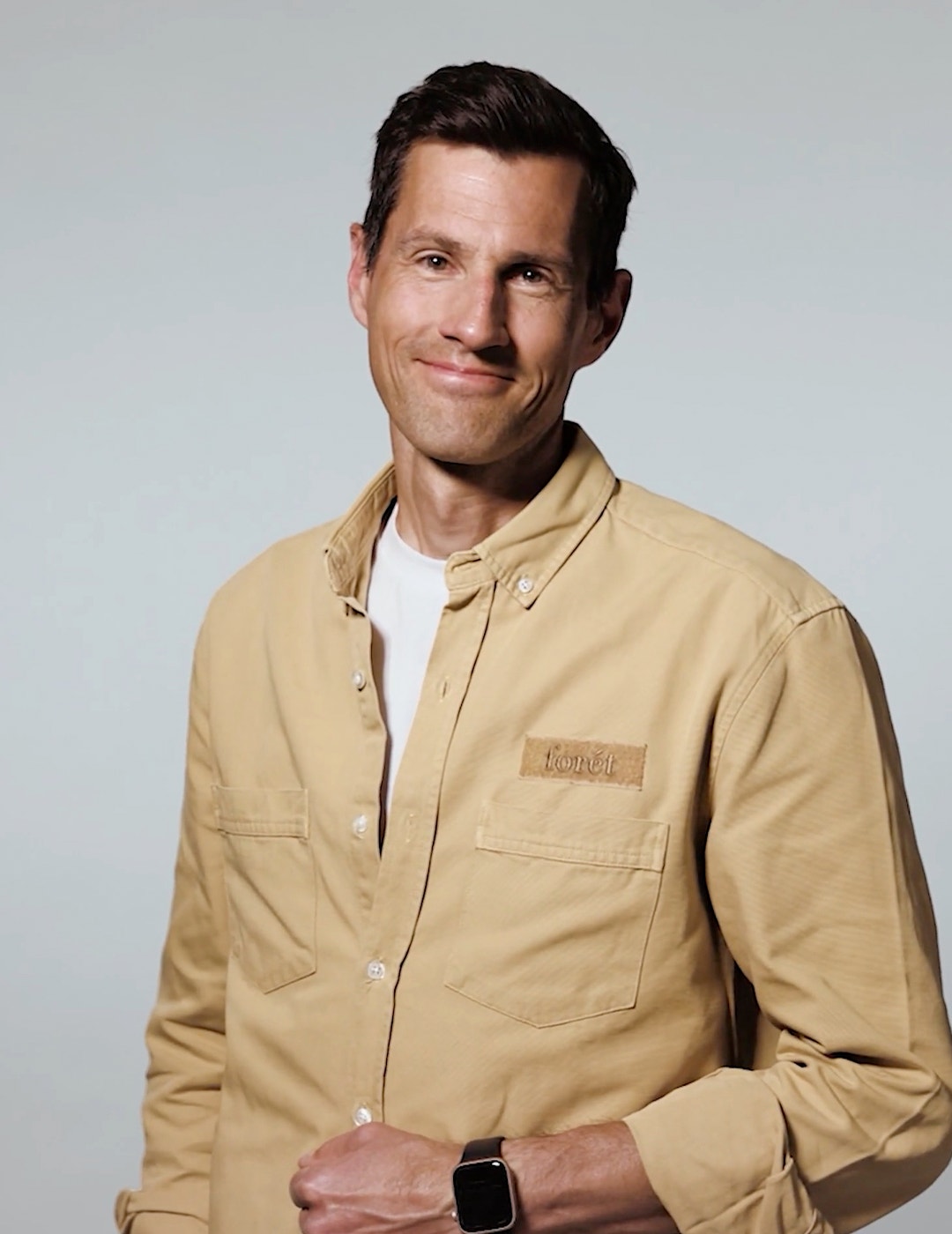 Porträttfoto av en man i beige skjorta mot grå bakgrund.