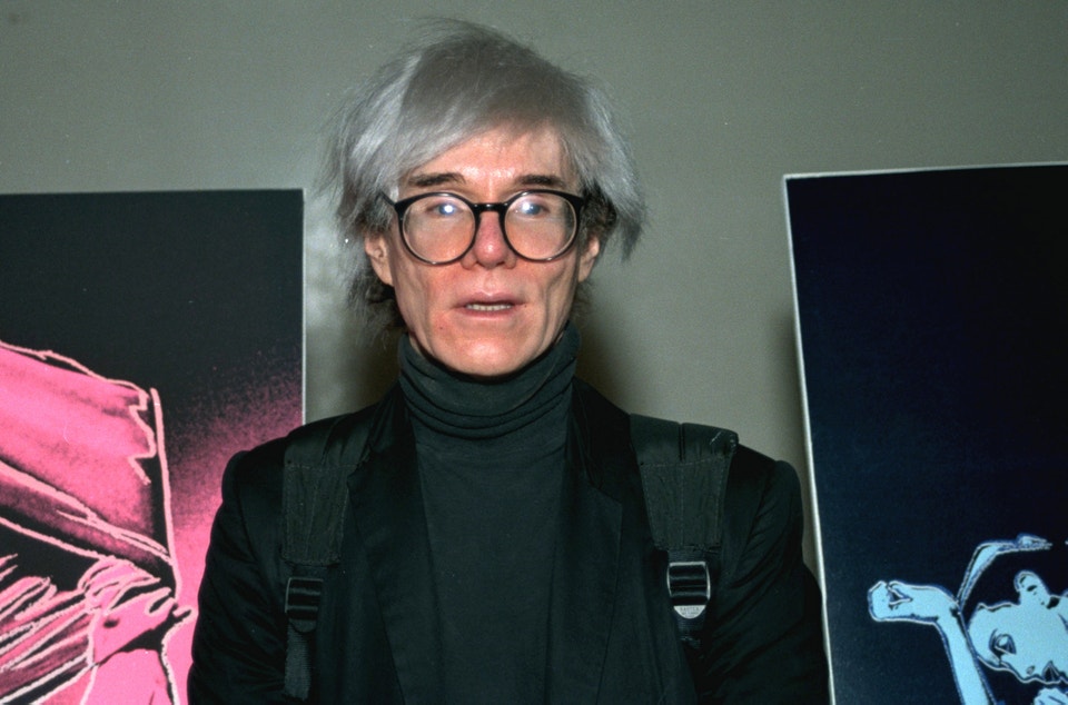 Konstnären Andy Warhol, i klädd svarta kläder och i silverfärgat hår.