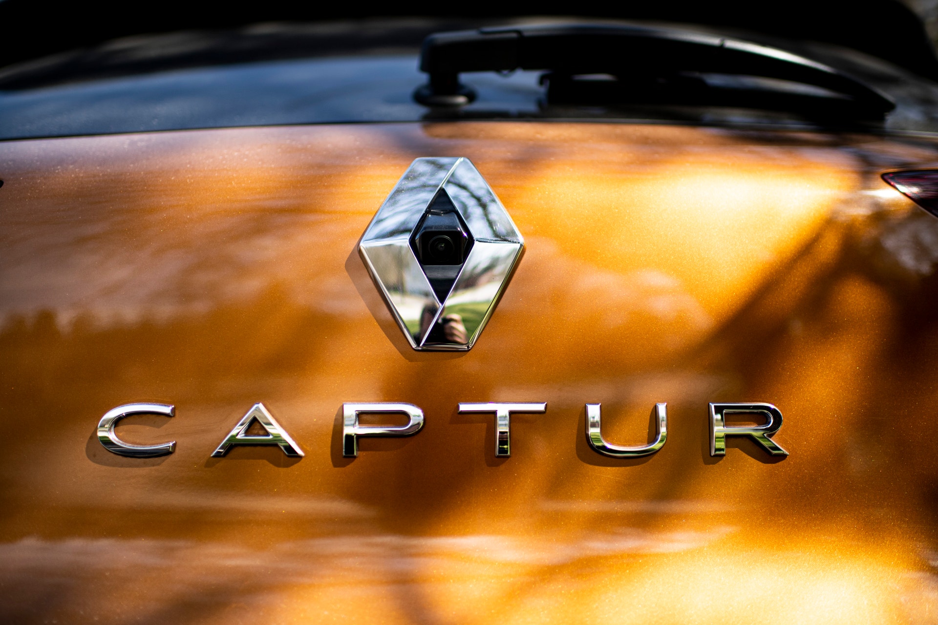 Baksidan av en orangebrun Renault Captur med Renaults logotyp och modellnamnet Captur i kromade bokstäver.