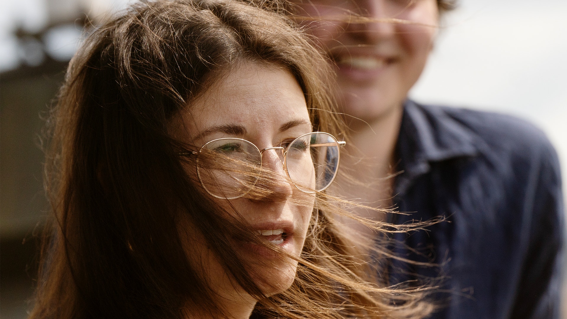 Hanna Andreen och Antonio Melani står på balkongen vid sitt kontor. Hannas hår flyger i vinden.