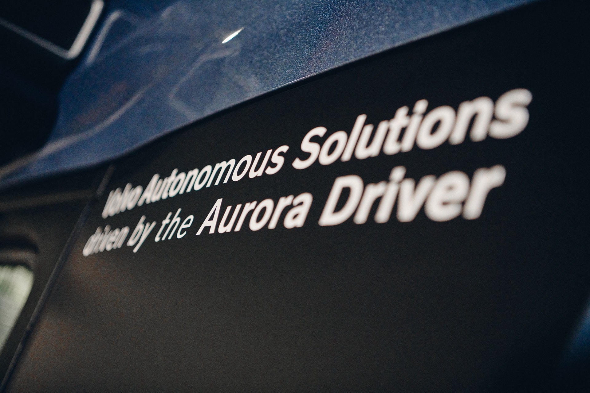 Text på en mörk yta som säger "Autonomous Solutions driven by the Aurora Driver".