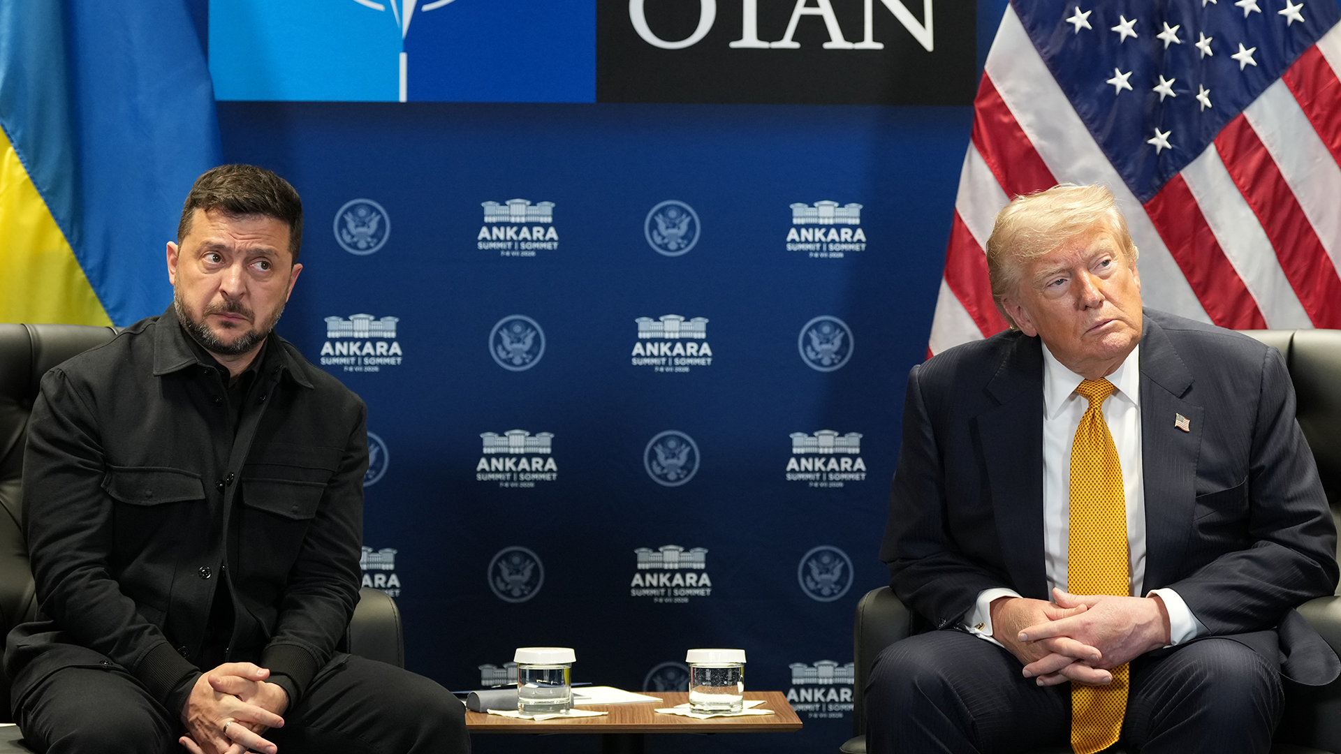 Donald Trump och Volodymyr Zelenskyj sitter bredvid varandra i fåtöljer och ser allvarliga ut. Bakom dem syns en Nato-skylt från toppmötet i Ankara, en amerikansk flagga och en ukrainsk flagga.