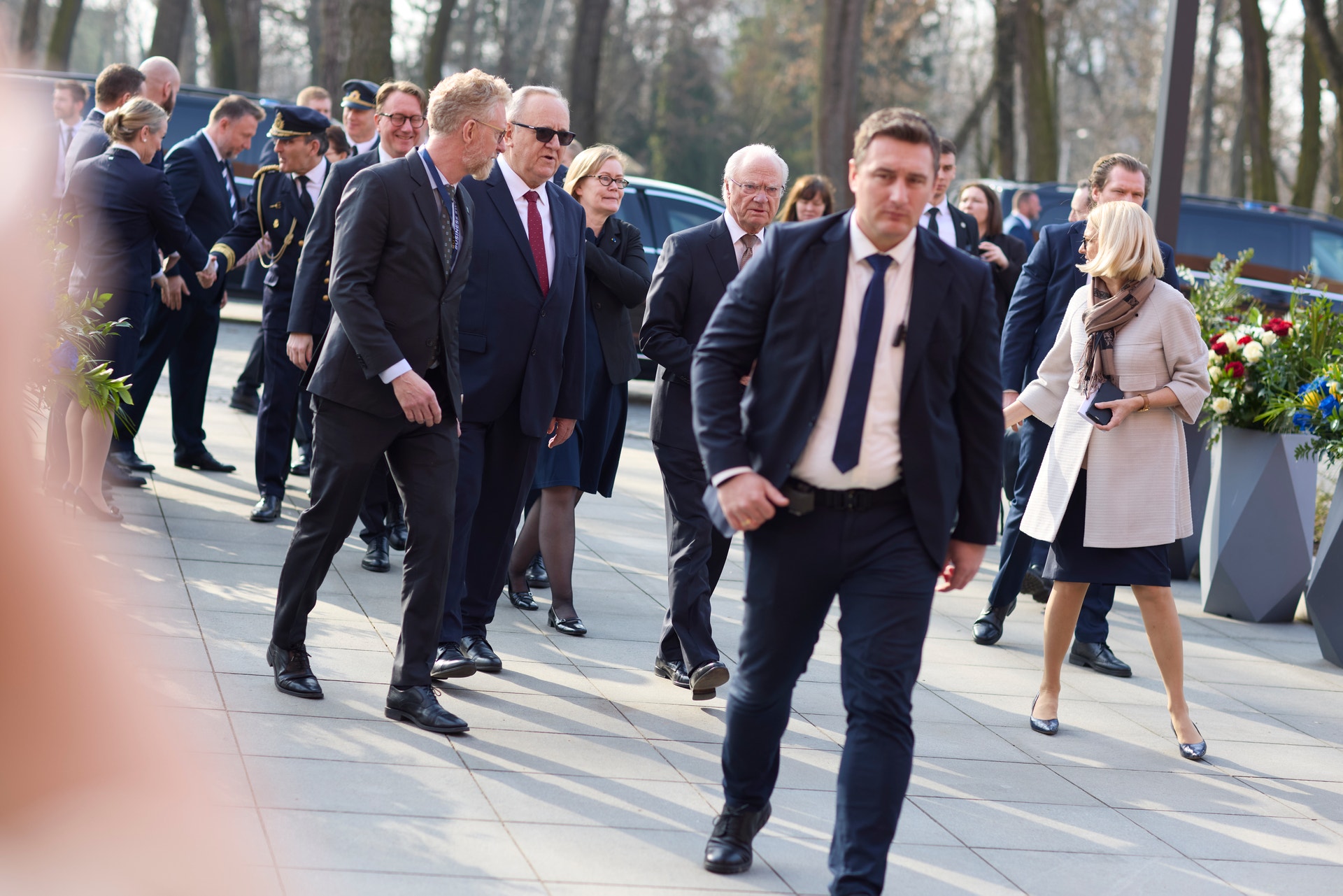 Grupp av formellt klädda personer som går tillsammans utomhus vid ett officiellt evenemang.