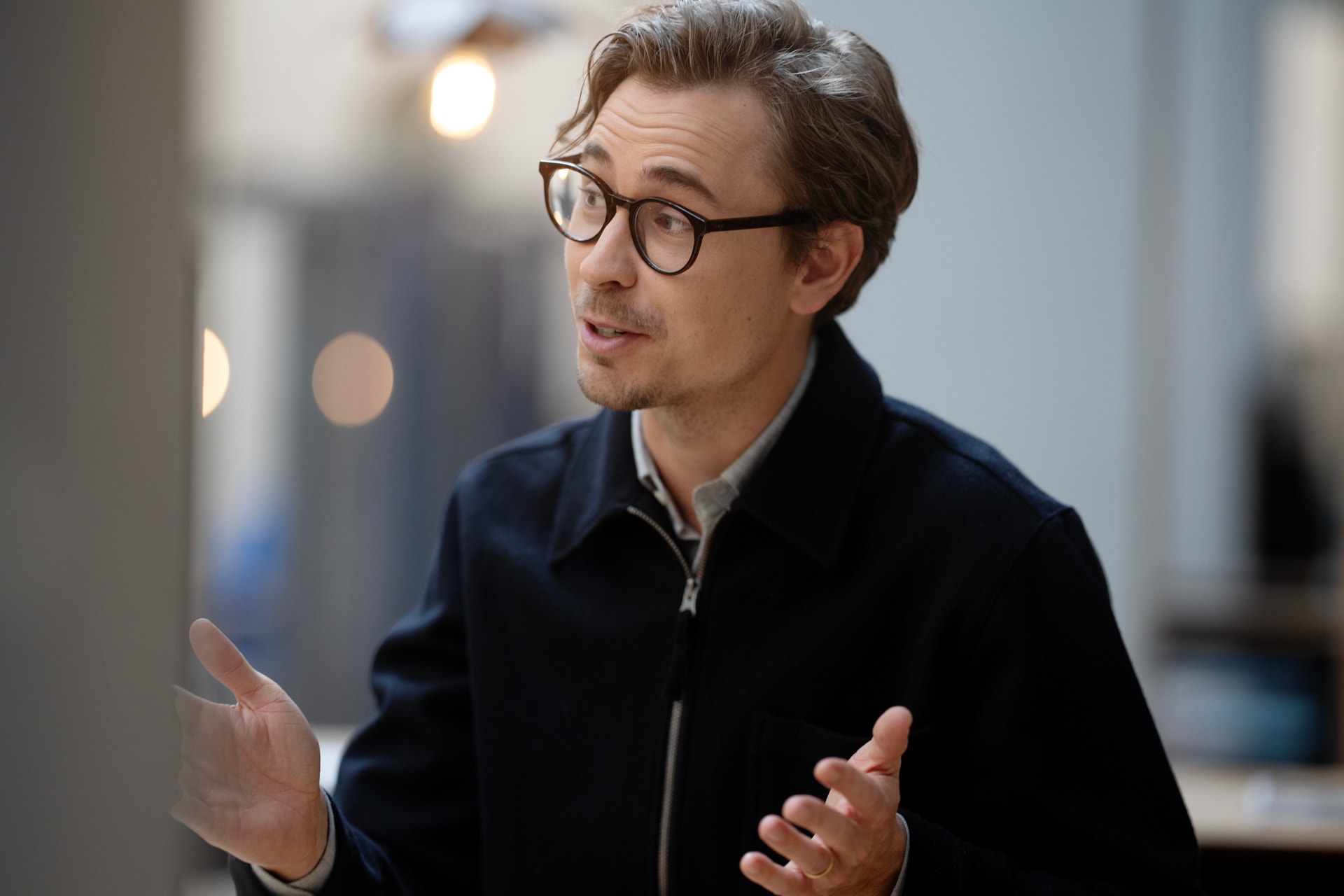 Porträtt av man med glasögon och mörkblå jacka som talar eller presenterar