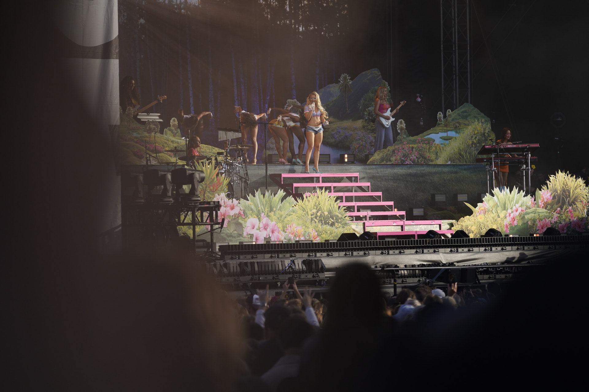 Zara Larsson uppträder på scenen under Way Out West-festivalen. Scenen är belyst med rosa trappor och omgiven av grönska. Publiken ses i förgrunden.