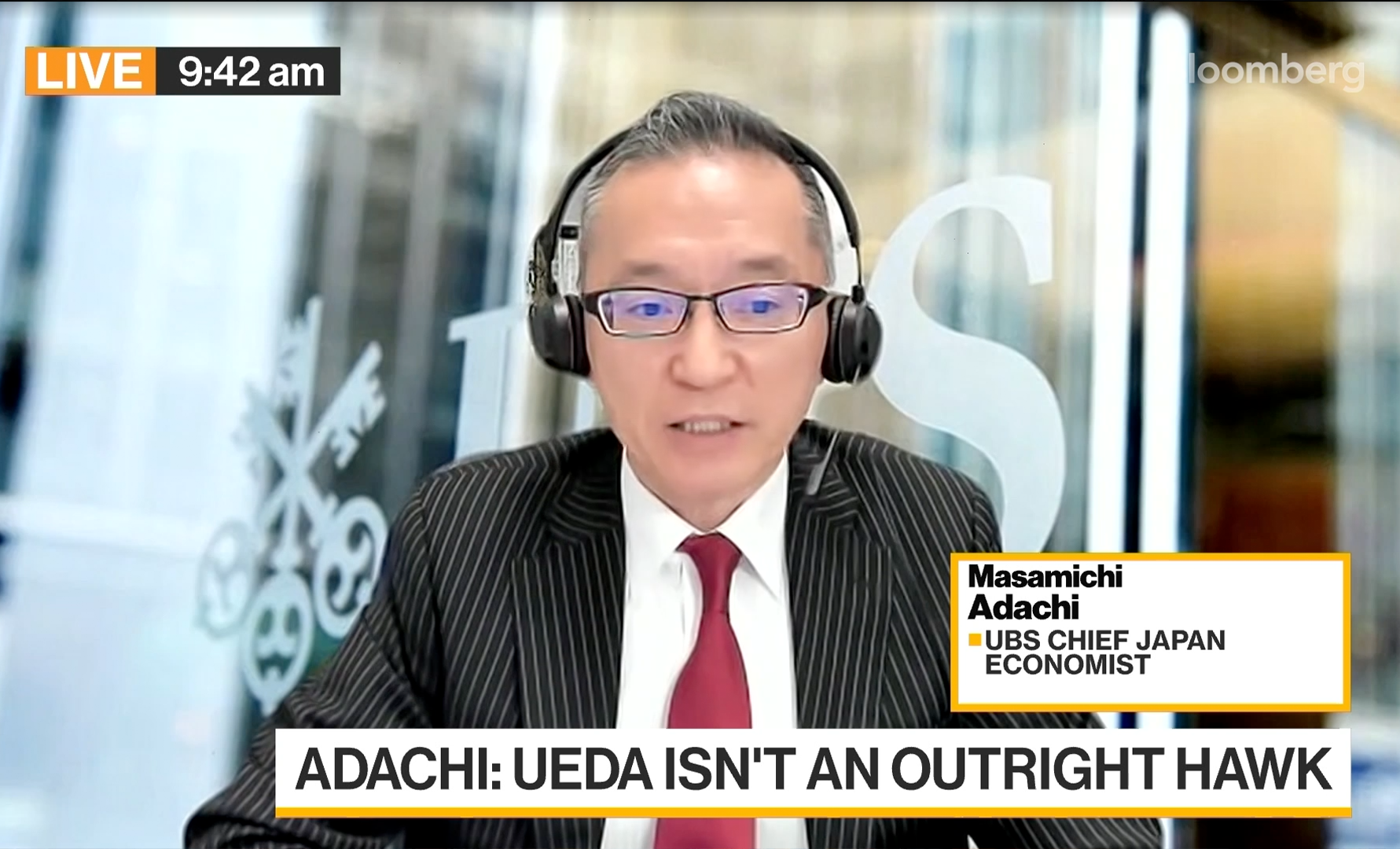 Man i kostym och glasögon med headset talar under en direktsänd intervju