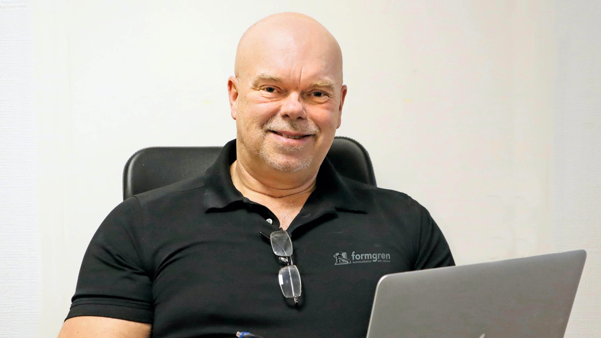 Porträttfoto av en man som sitter vid ett skrivbord med en laptop framför sig.