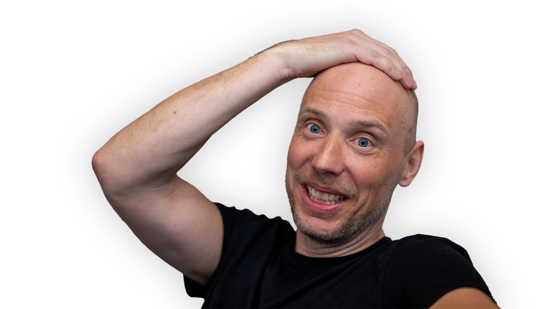 John Skogman ser glad ut. Han tar sig på huvudet. Han har svart t-shirt. 