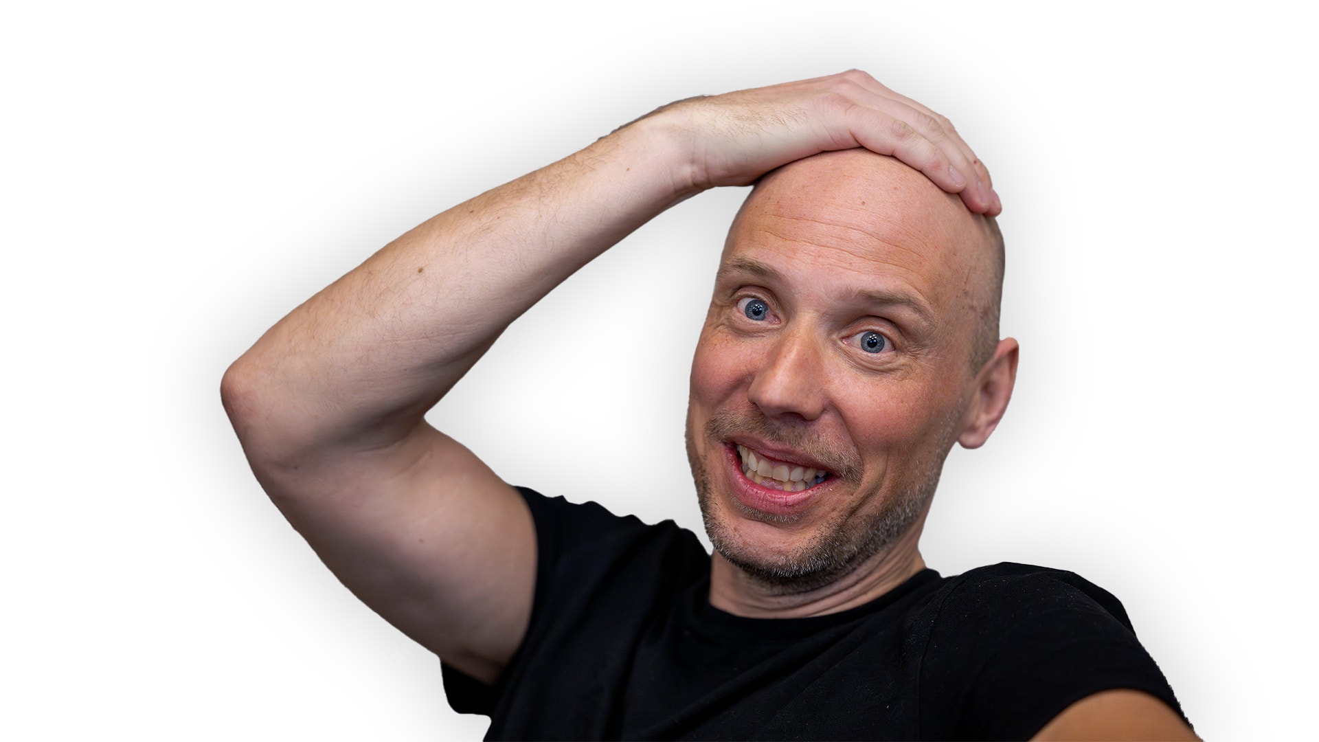 John Skogman ser glad ut. Han tar sig på huvudet. Han har svart t-shirt. 