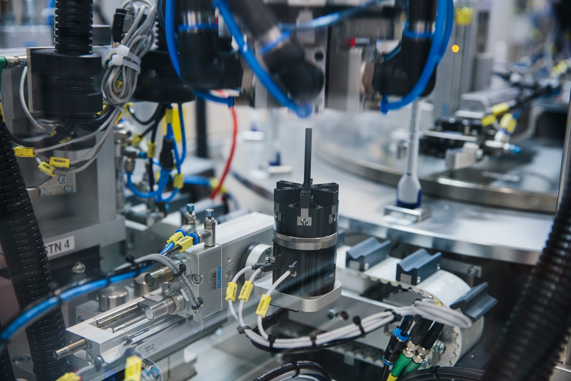 Närbild av en industriell produktionslinje med blå och svarta komponenter, motorer och elektroniska delar monterade på en metallram.