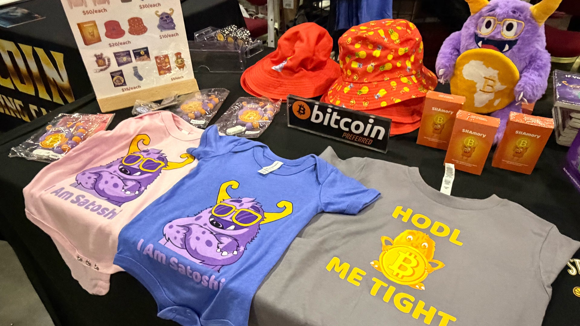 Bord med Bitcoin-relaterad merchandise inklusive t-shirts, kepsar och böcker om kryptovalutor