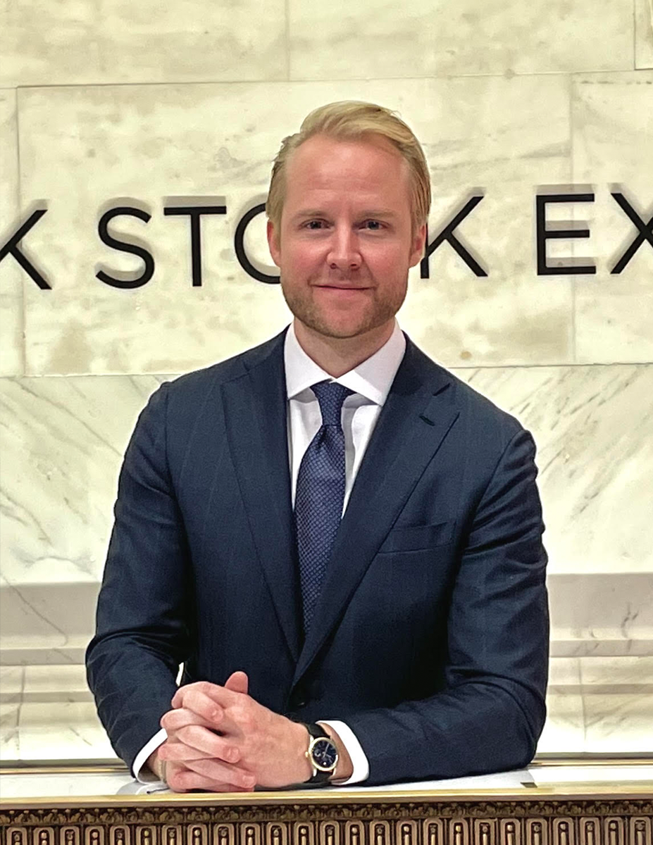 Hannes Östlund på SEBs kontor i new york. Han sitter i blå kostym och blå slips mot en ljus marmorbakgrund.