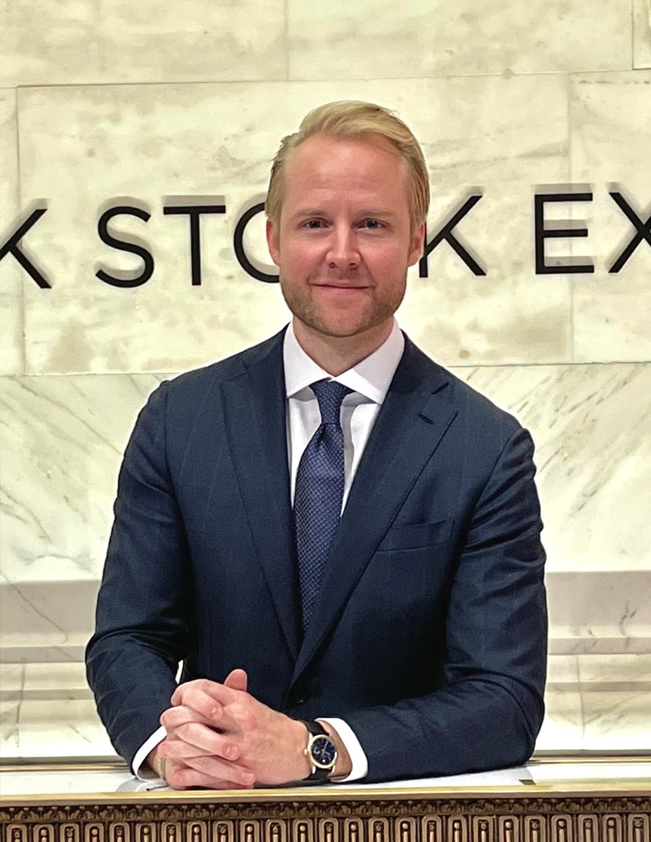 Hannes Östlund på SEBs kontor i new york. Han sitter i blå kostym och blå slips mot en ljus marmorbakgrund.