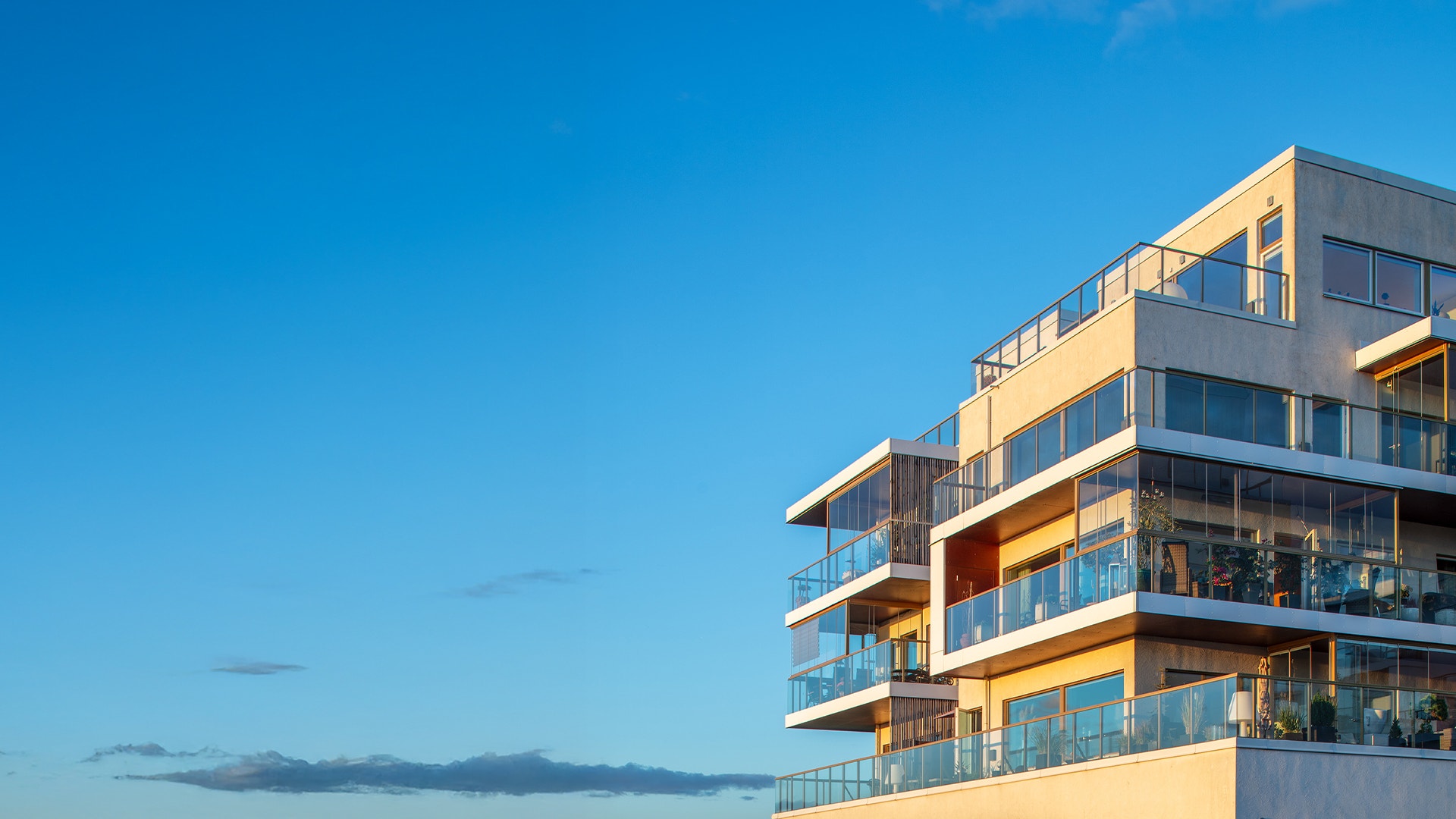 Modernt flerbostadshus med gula och grå fasader mot blå himmel