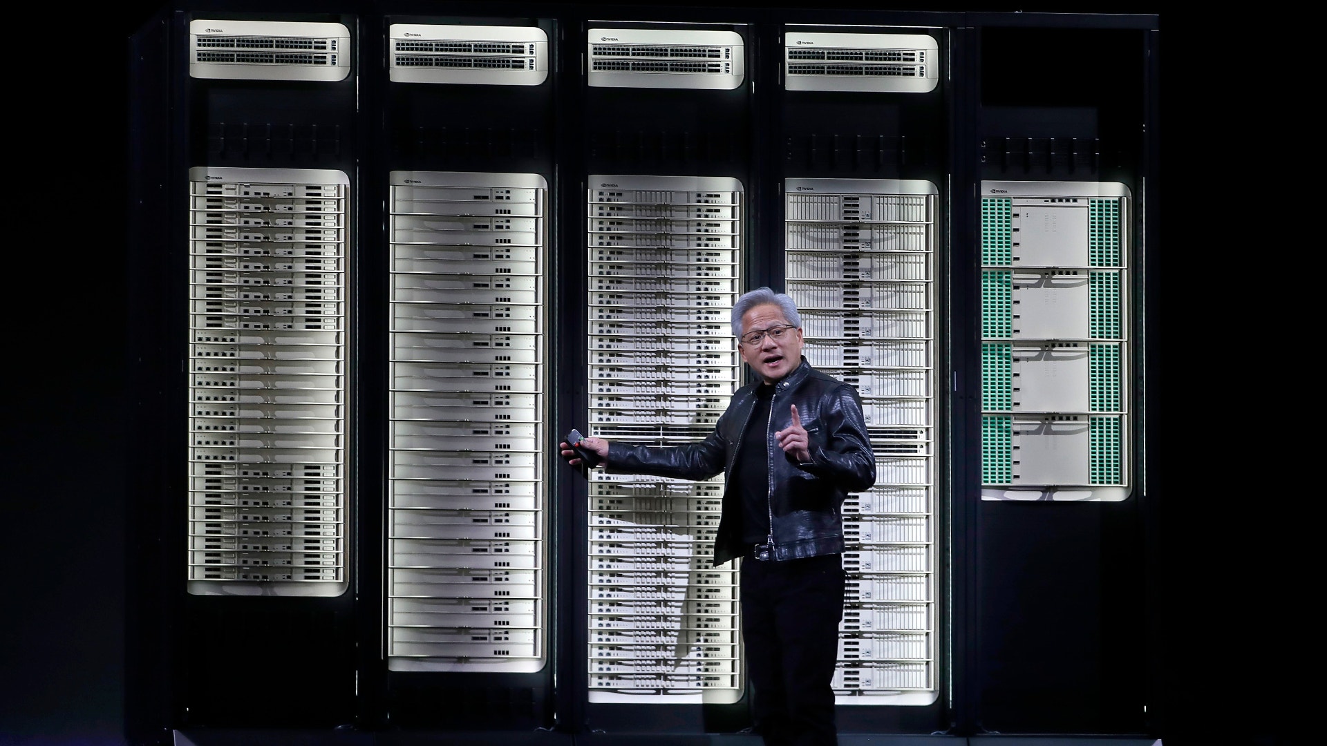Man i mörk kavaj presenterar framför serverrack och datorsystem