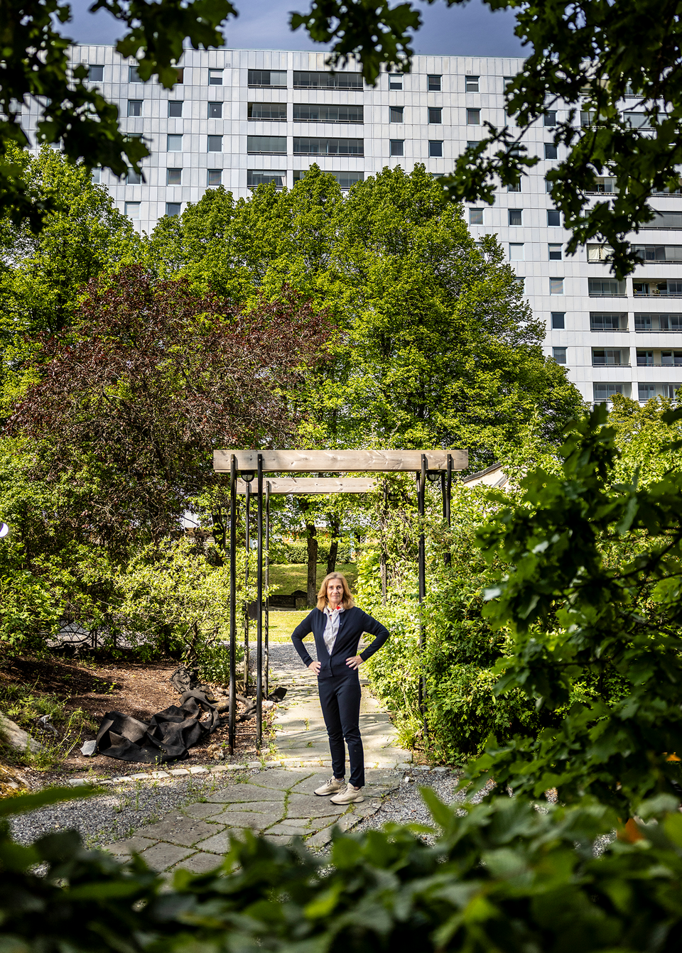 Anette Frumeri står i en trädgård framför en av Rikshems fasader. 