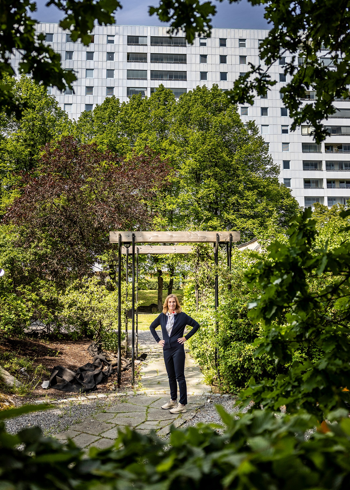 Anette Frumeri står i en trädgård framför en av Rikshems fasader.