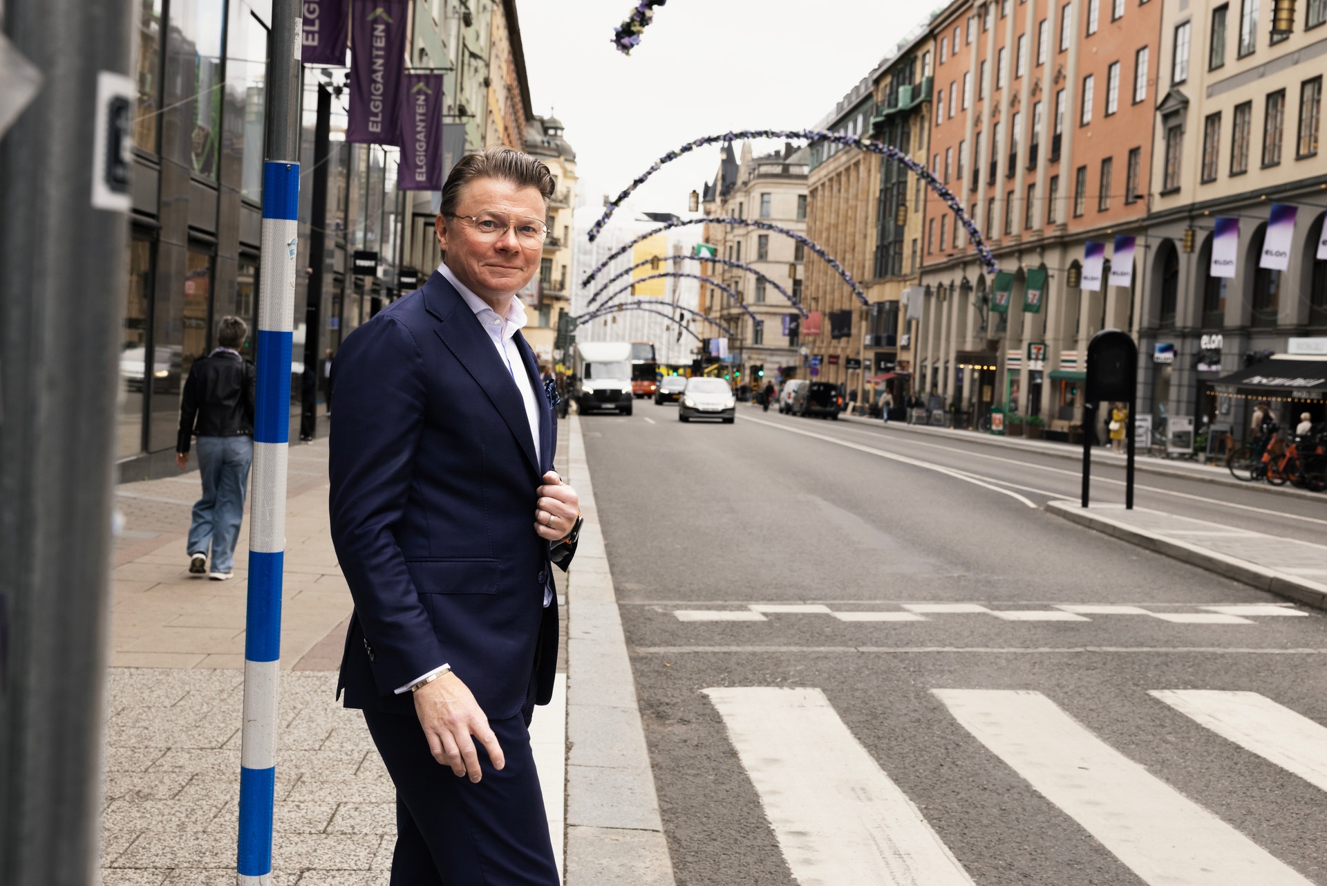 En man i kostym står på en gata i en storstad.