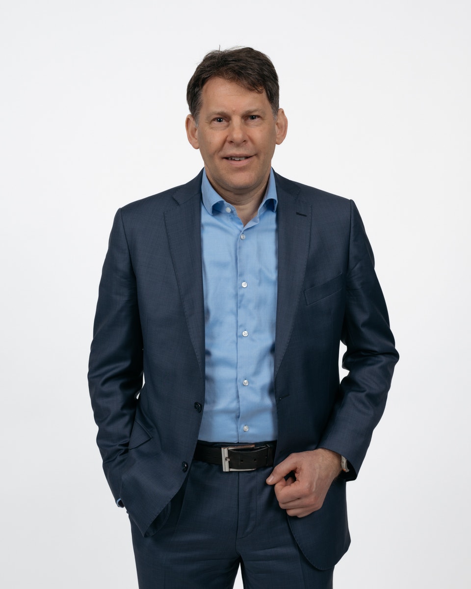 Porträtt av en Kevin Dalby i mörkblå kostym och ljusblå skjorta mot neutral bakgrund