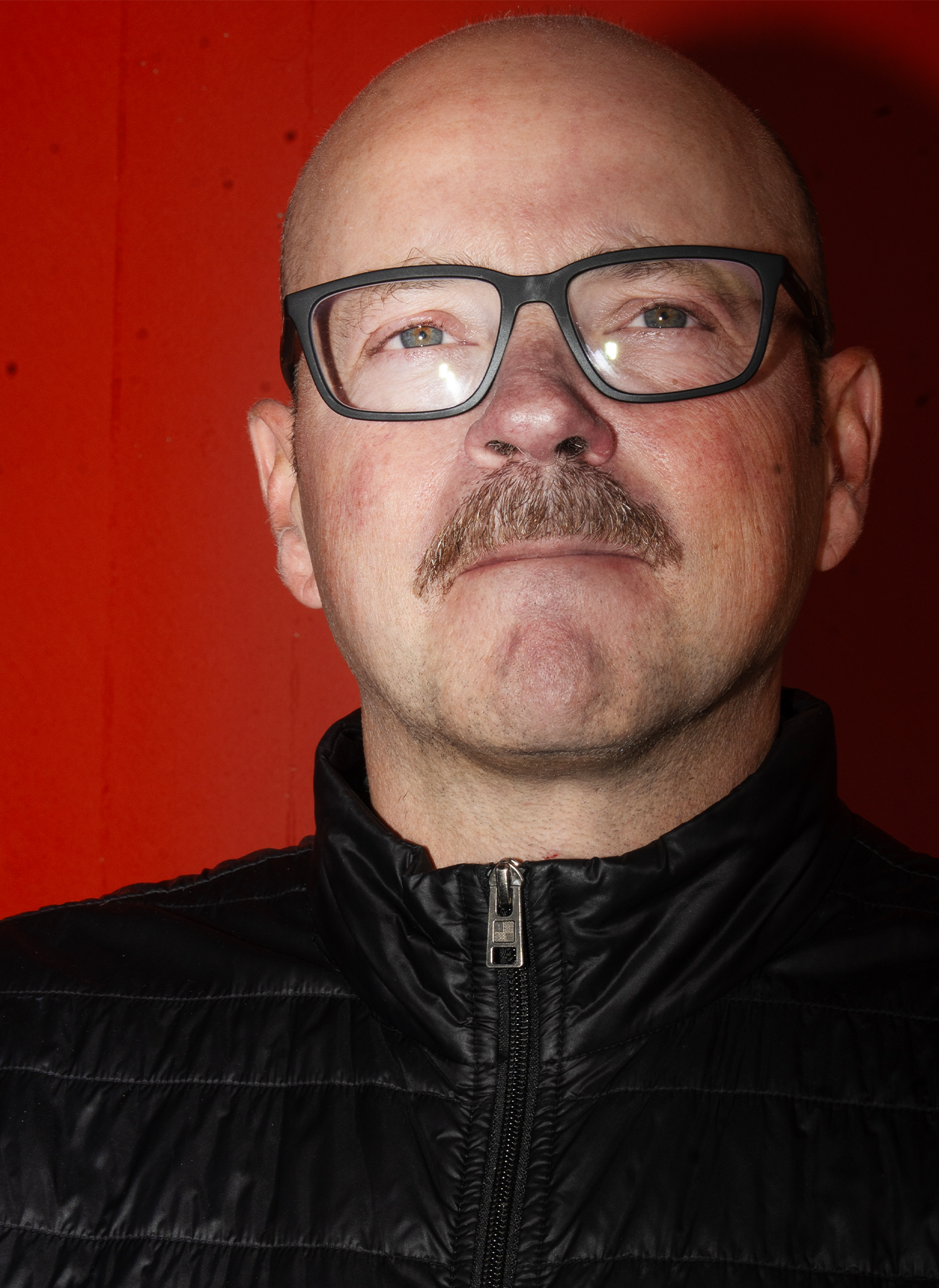 Närbild på Pål Ahlsén mot en röd bakgrund. 