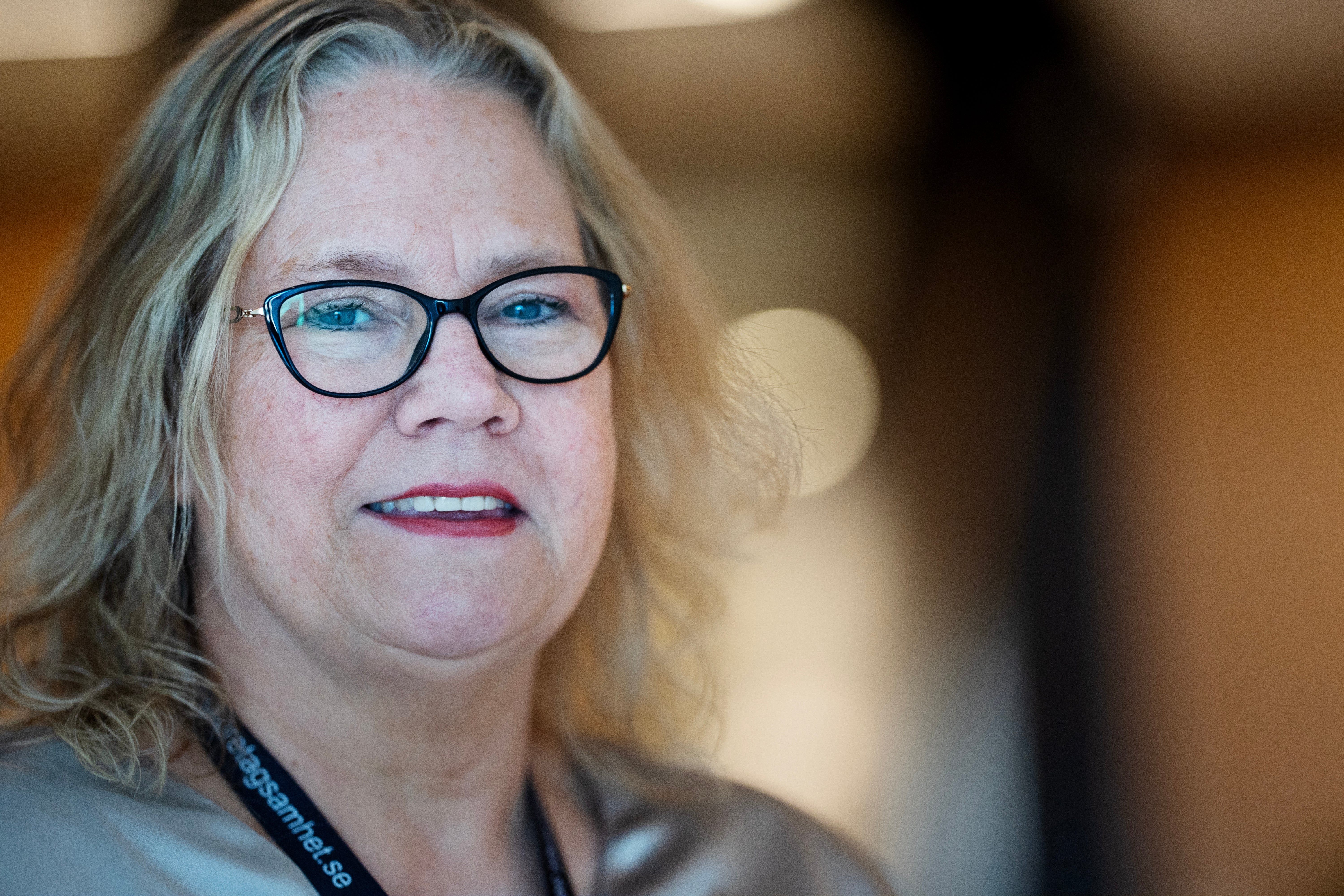 Porträtt av en kvinna med glasögon och långt gråblont hår som ler mot kameran.