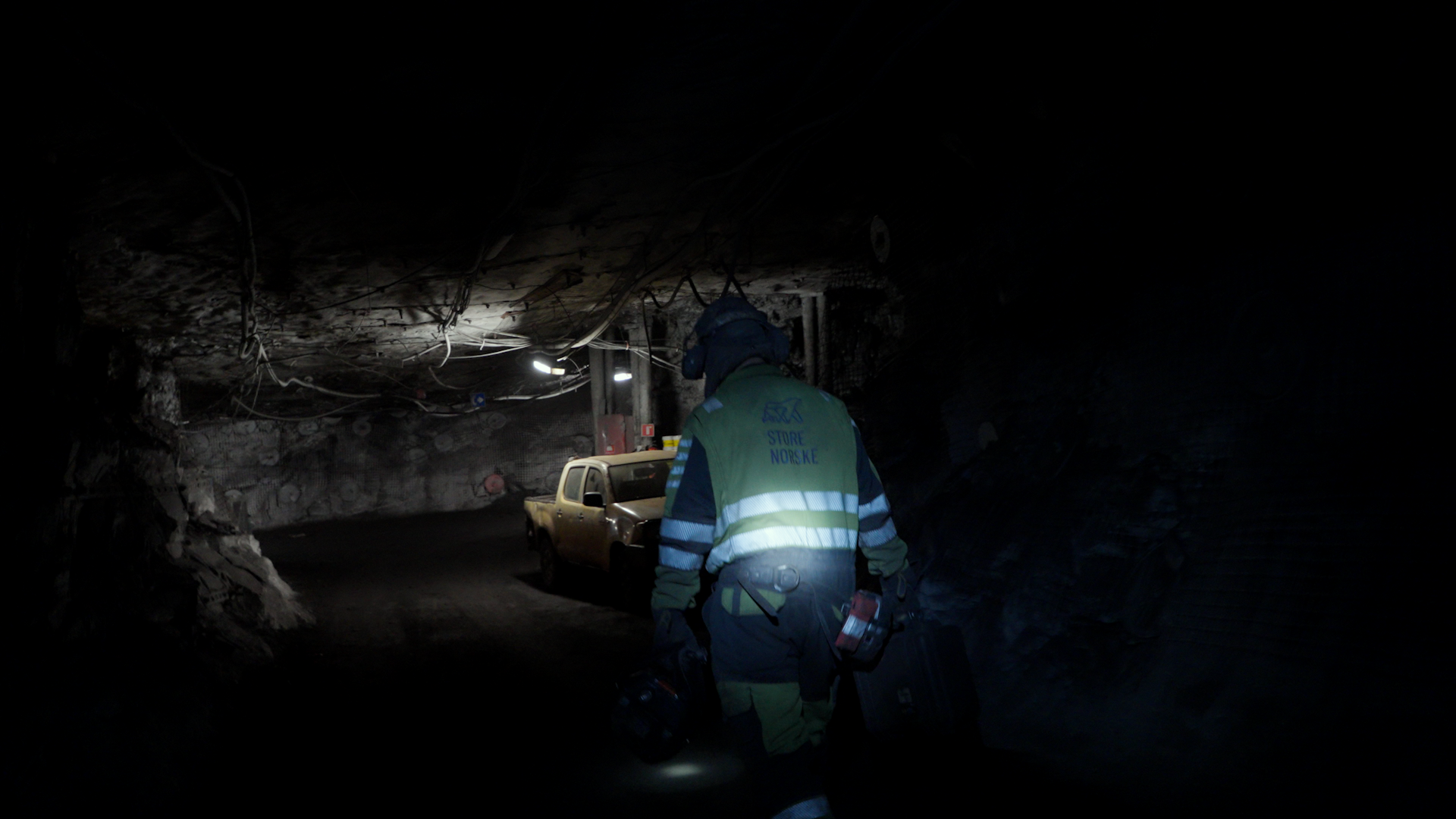 Det är kolsvart nere i gruvan där arbetarna jobbet. I taket hänger en liten lös lampa i en sladd. 