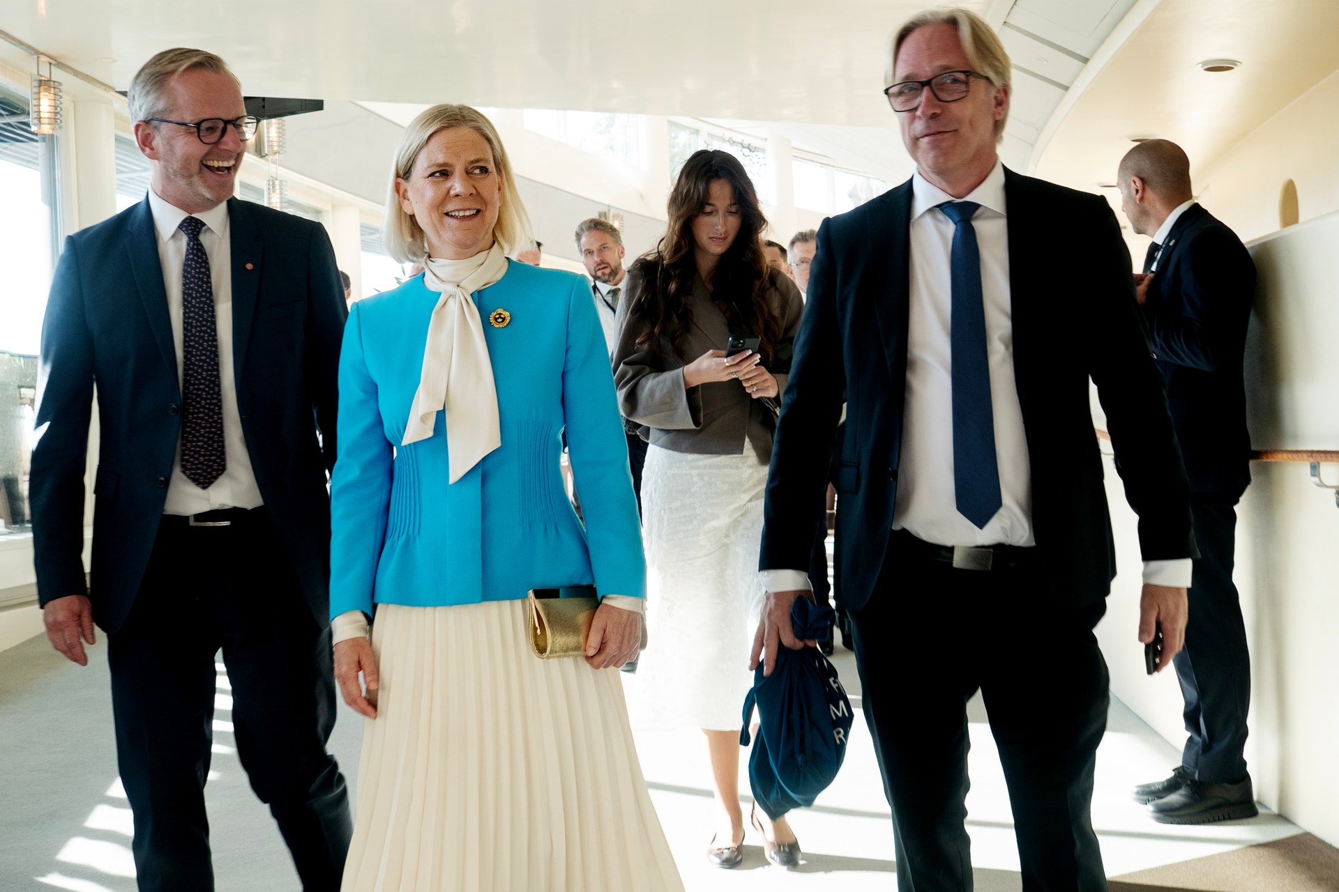 Magdalena Andersson går tillsammans med andra personer i en ljus korridor, troligen i Riksdagshuset.