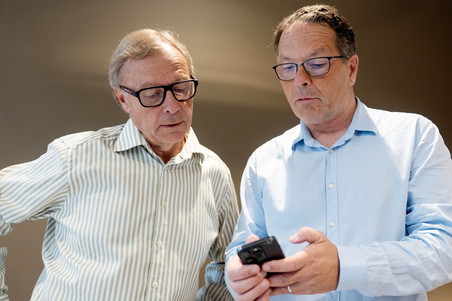 Två män tittar tillsammans på en mobiltelefon.