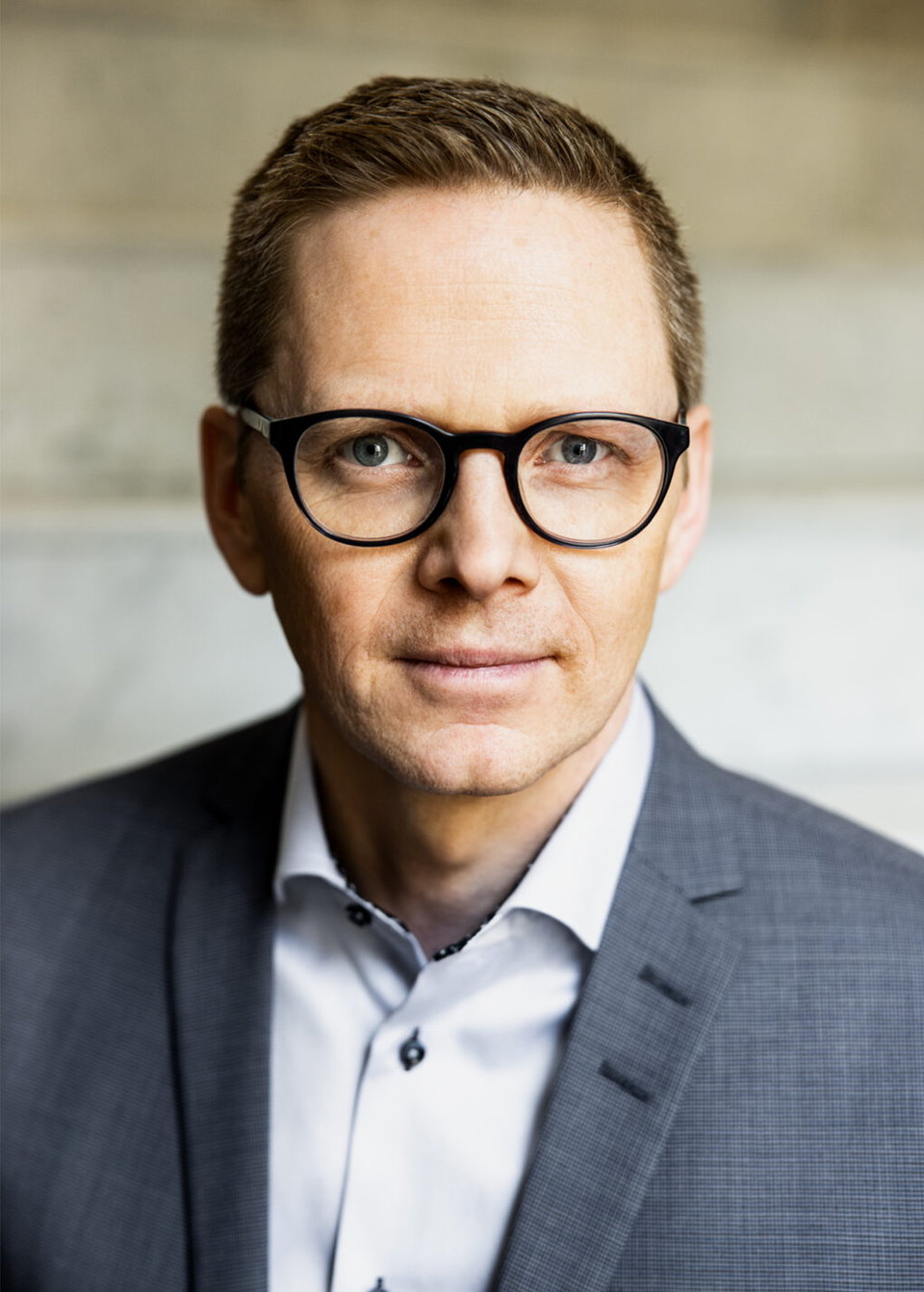 Andreas Mörck i en porträttbild. Han har svarta glasögon, vit skjorta och grå kavaj.