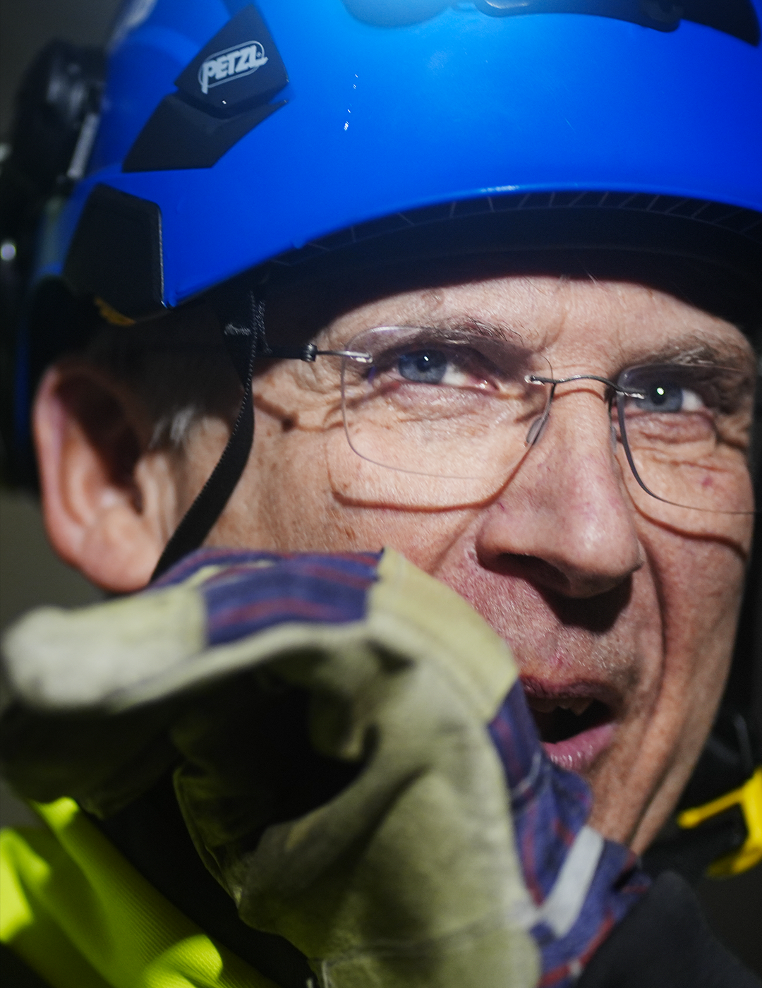 Man med blå klätterhjelm och glasögon i utomhuskläder