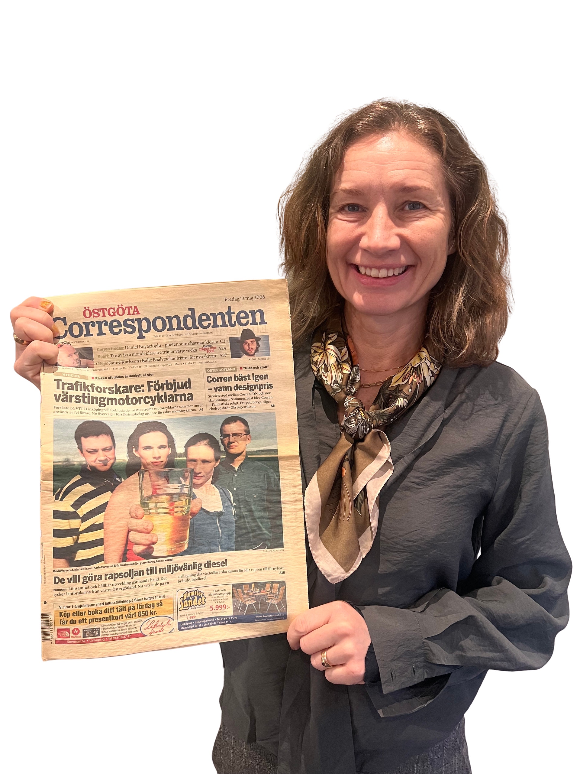 Leende kvinna med axellångt hår och sjal håller upp en tidning, Östgöta Correspondenten.
