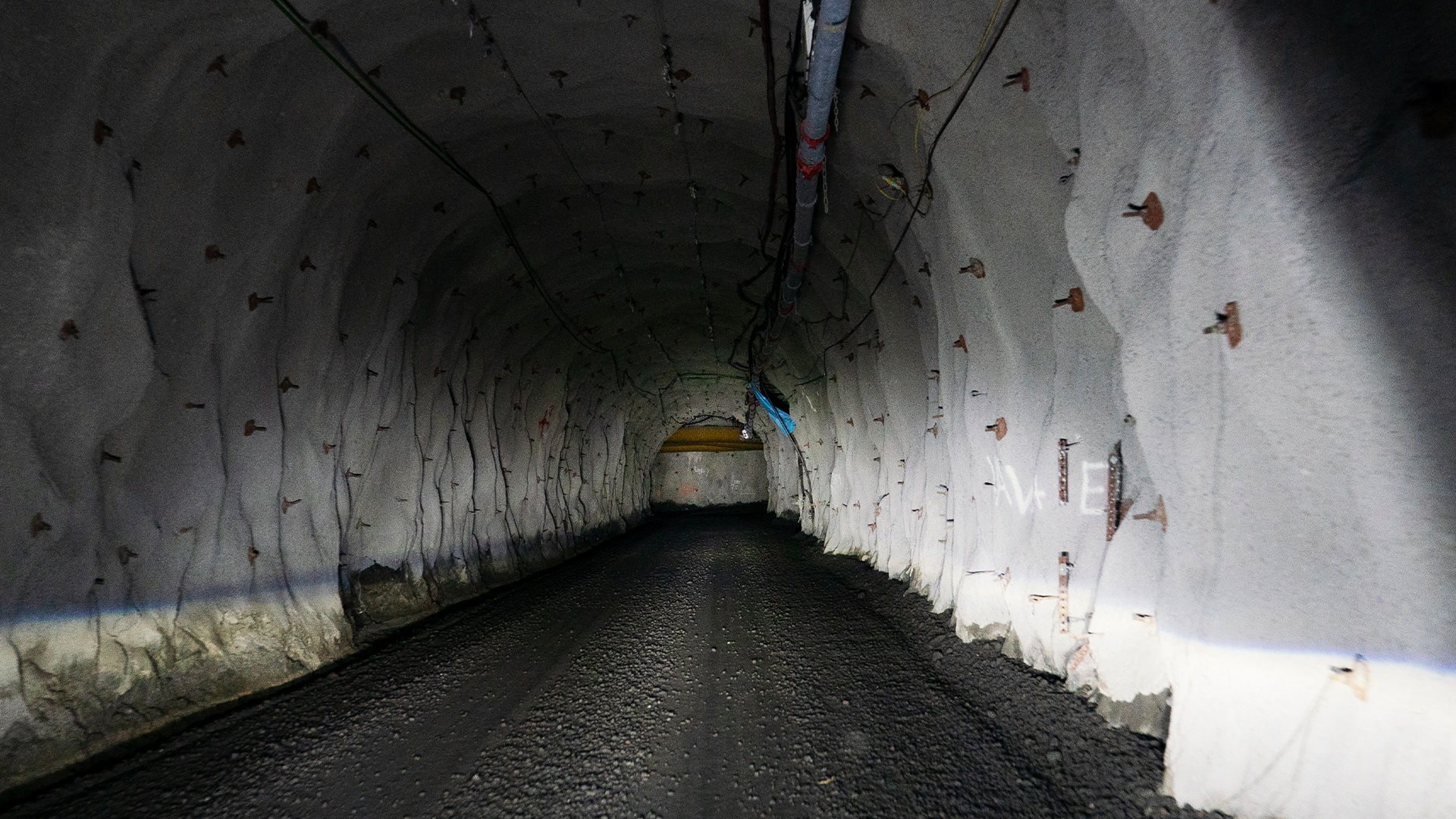 En tunnel med vita väggar och svart asfaltväg som sträcker sig in i mörkret