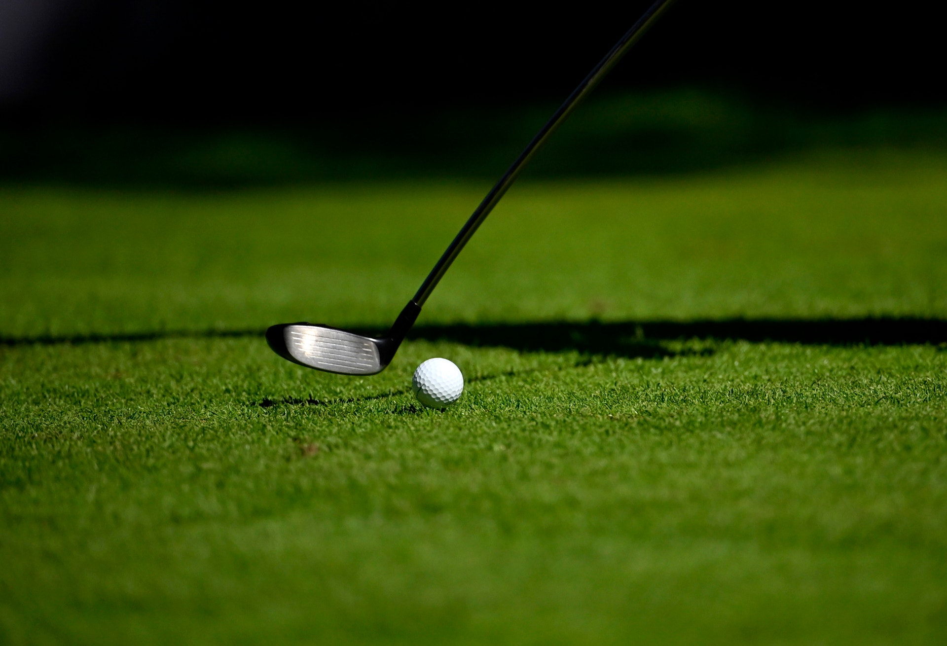 Golfklubba och golfboll på en grön gräsmatta.