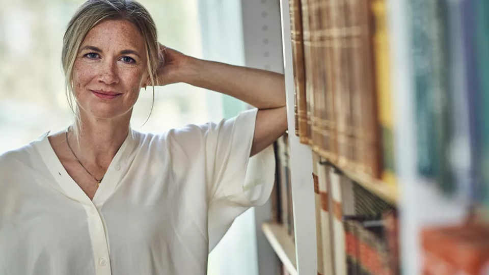 Kerstin Enflo lutar sig mot en bokhylla i biblioteket.