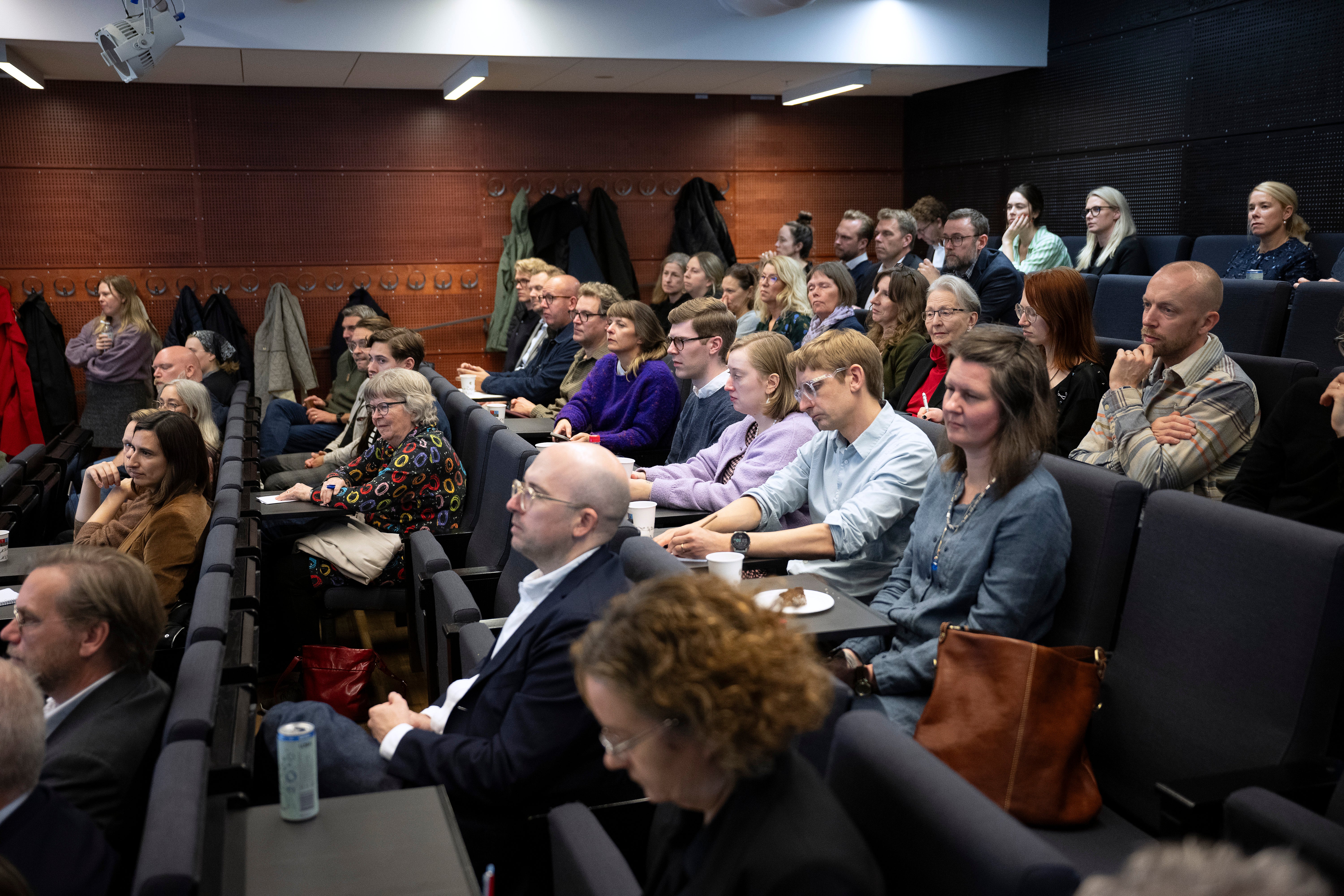 Publik som sitter i en föreläsningssal och lyssnar uppmärksamt.
