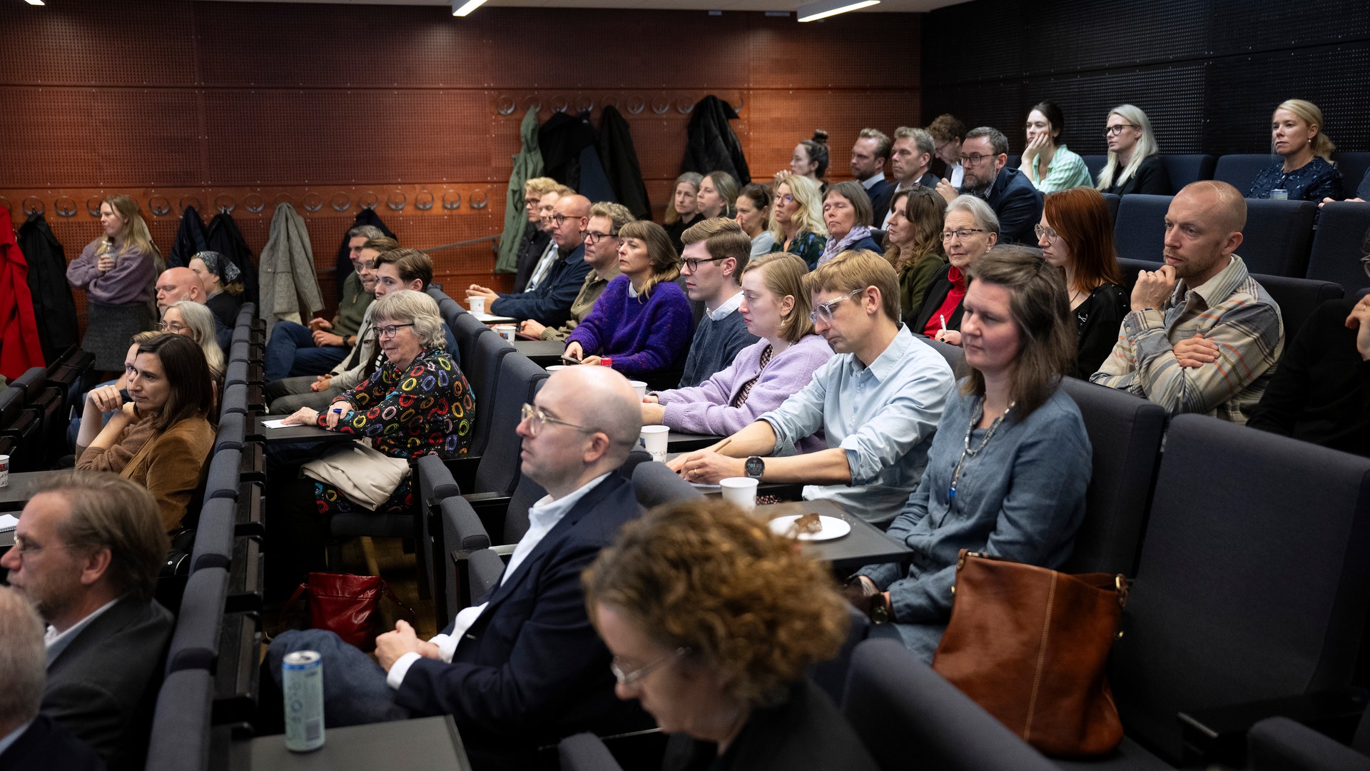 Publik som sitter i en föreläsningssal och lyssnar uppmärksamt.