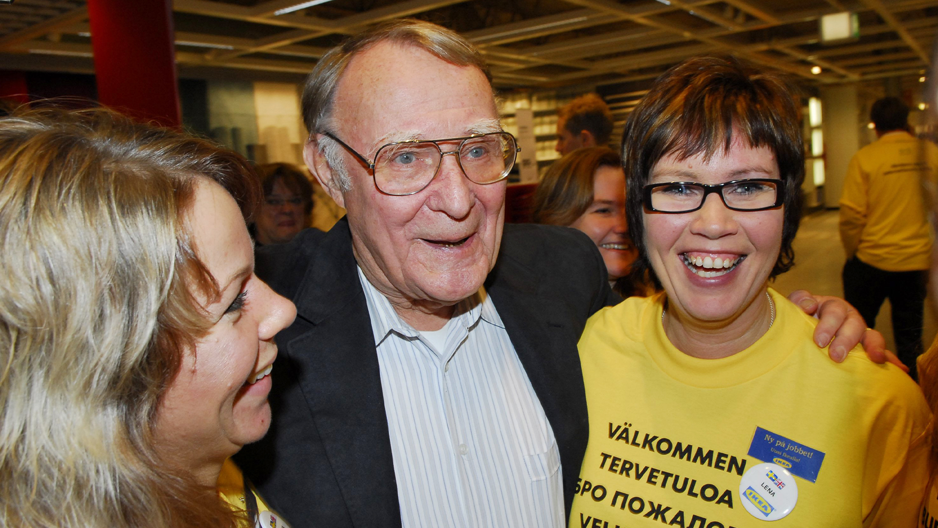 Tre personer som samtalar och ler vid ett evenemang inomhus.