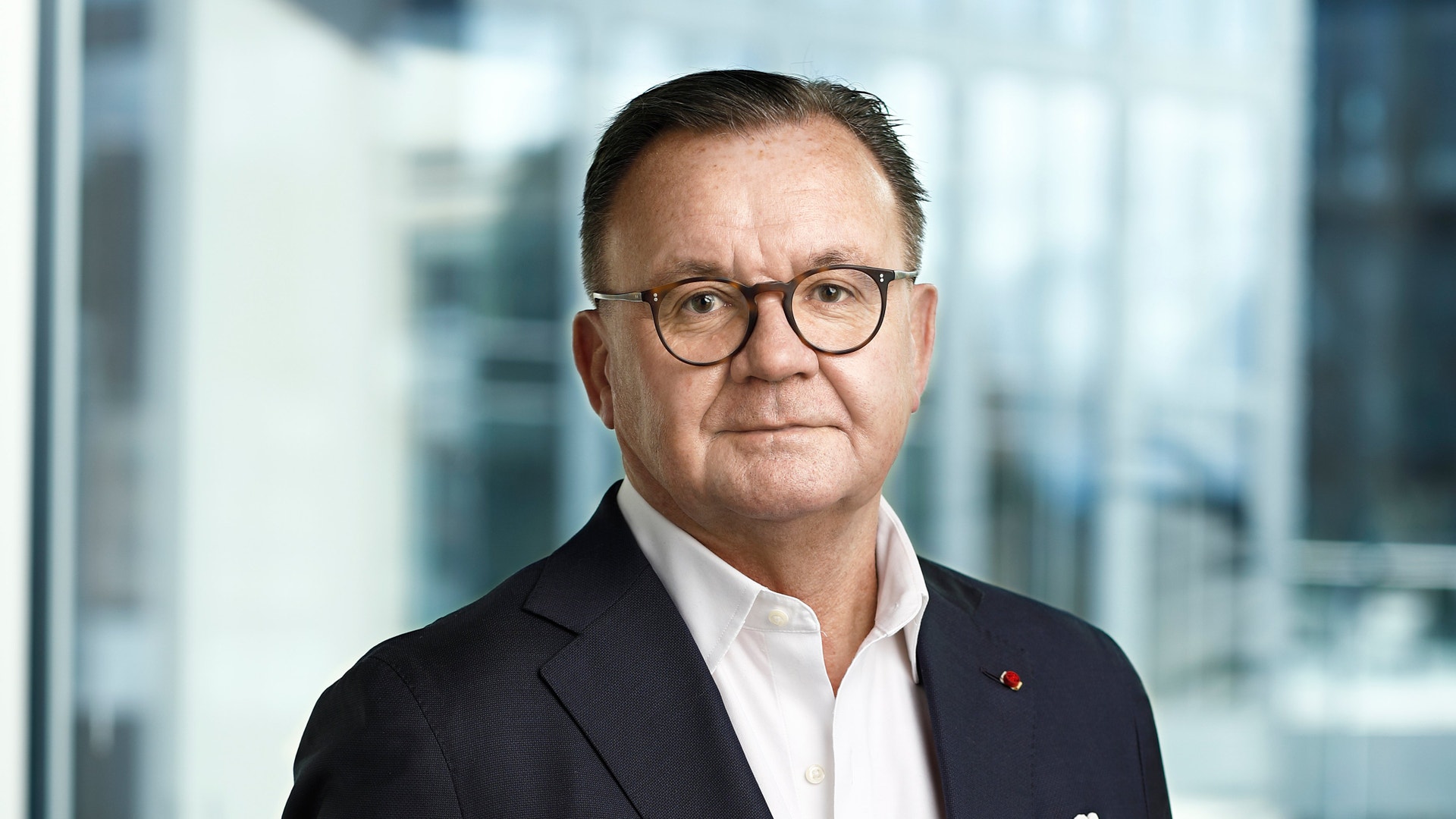 Porträtt av Karl-Henrik Sundström, man med glasögon och mörk kostym mot en suddig kontorsbakgrund.