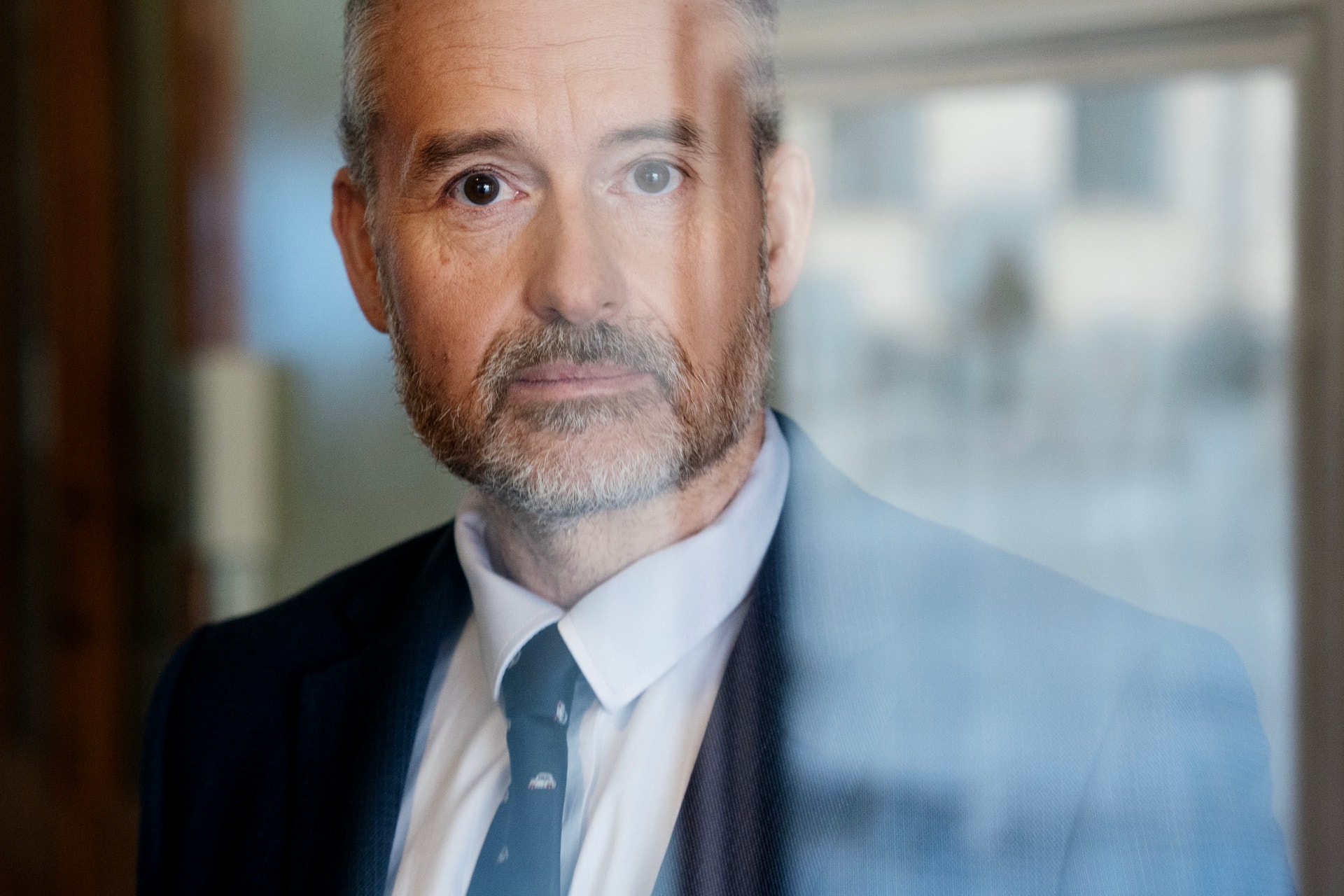 Porträtt av en man i kostym och slips framför ett fönster