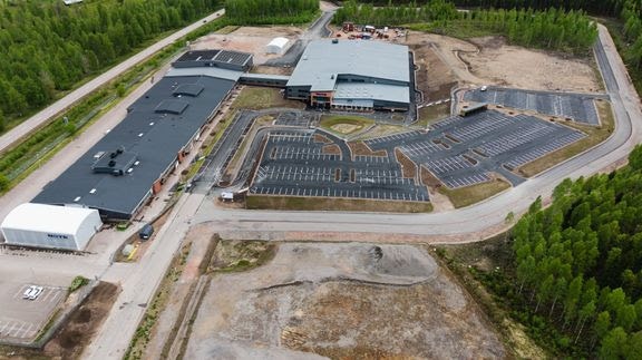 Flygfoto över Note fabrik i Torsby. Bilden visar fabriksbyggnader, en stor parkering och omgivande skogsmark.