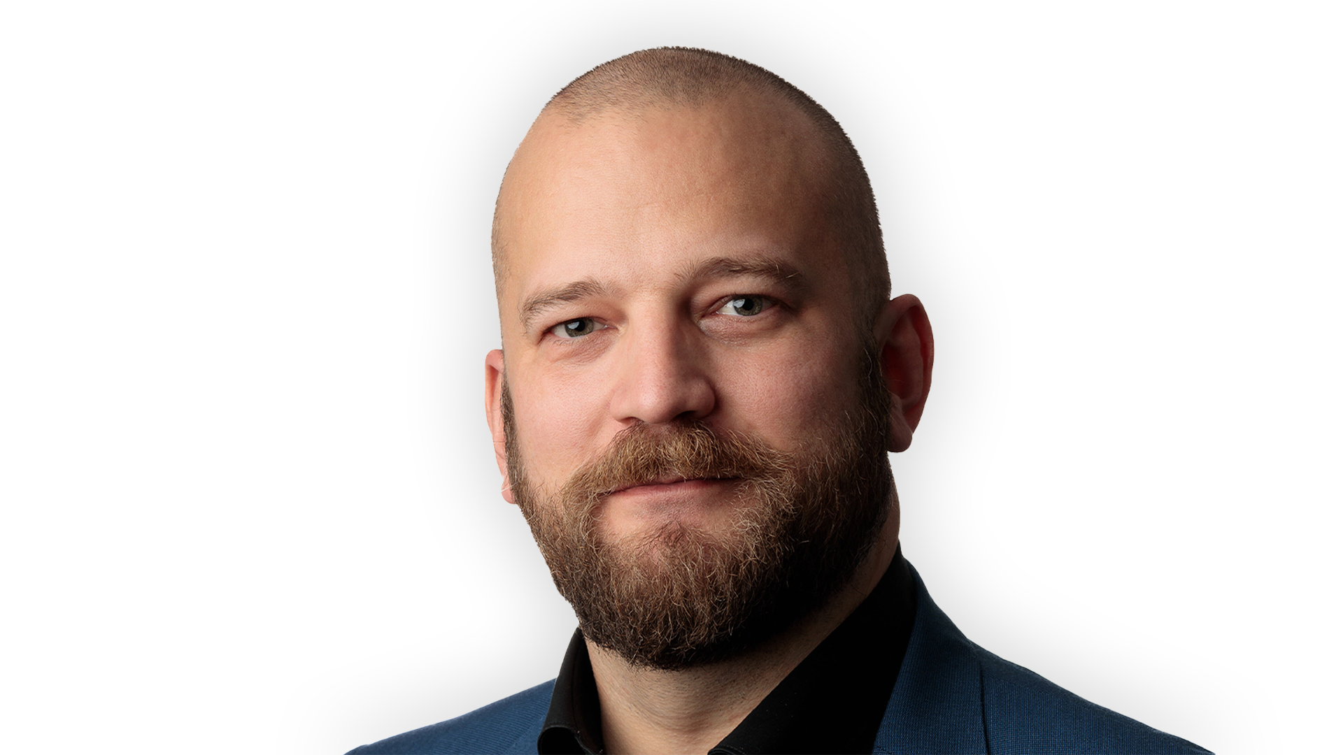 Richard bråse tittar in i kameran. Han ler med stängd mun. 