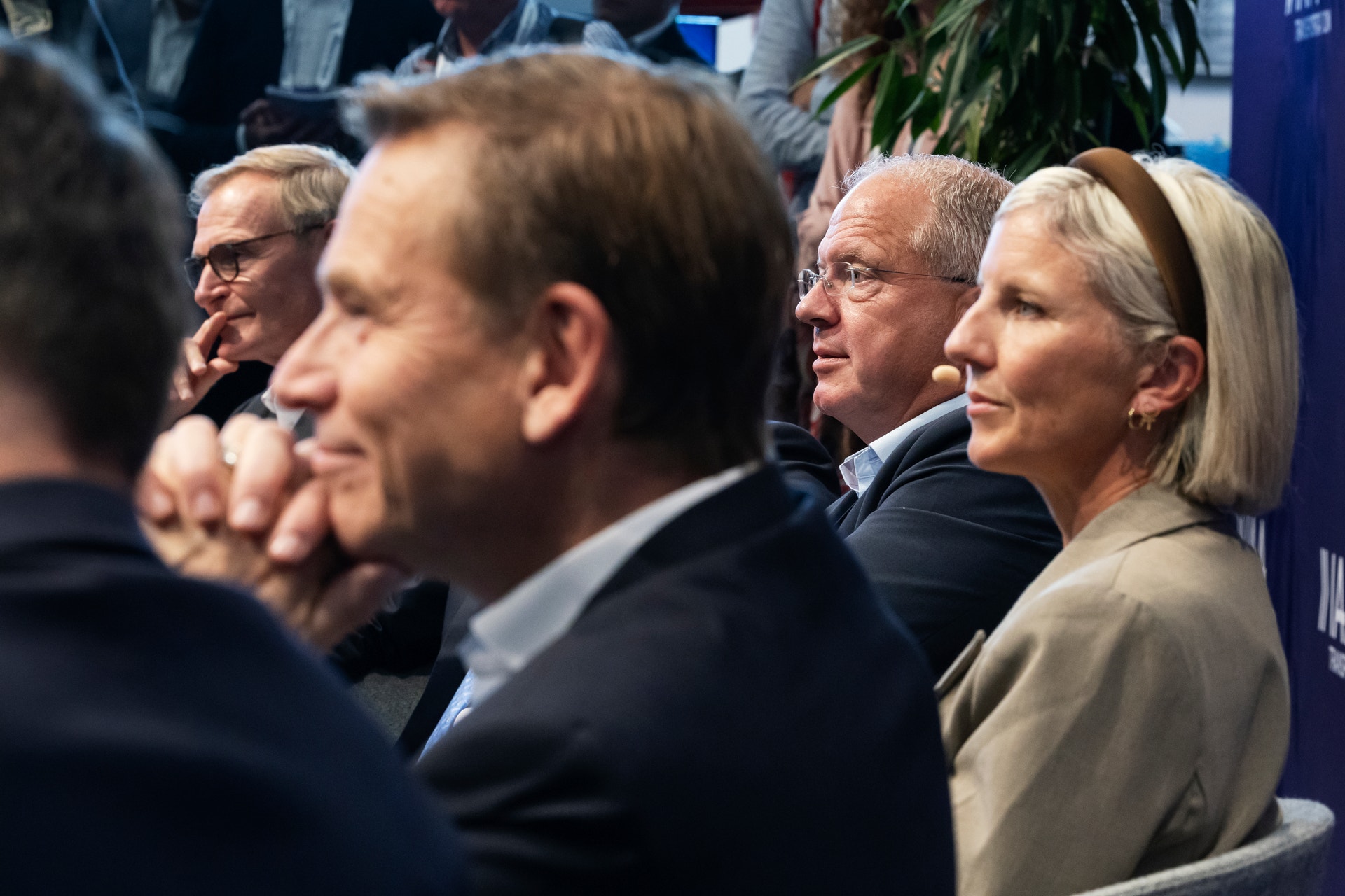 Personer sitter i publiken på en konferens och lyssnar uppmärksamt.