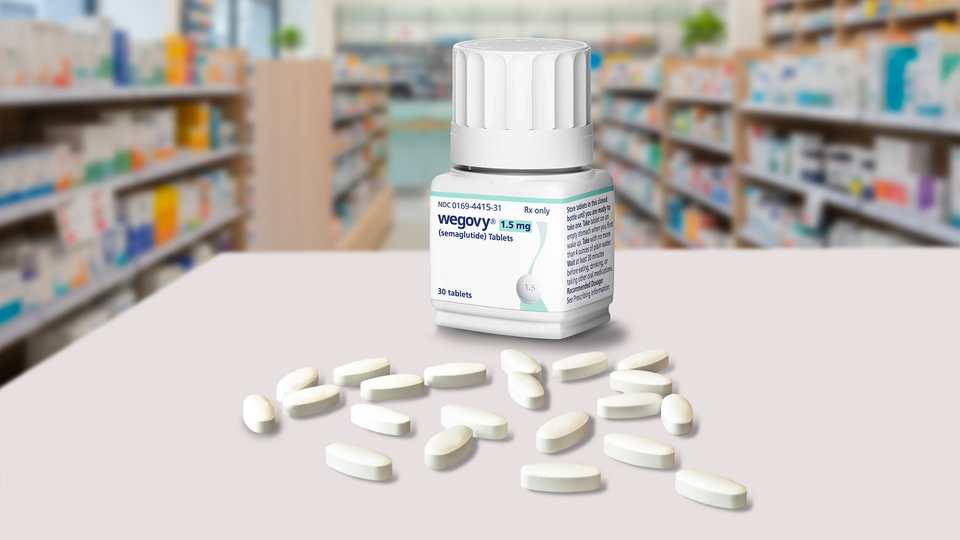 En medicinflaska med vita tabletter utspridda framför den på en vit yta, med apotek i bakgrunden.